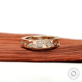 Low-profile mix-shape stone band shown angled on wooden surface.
