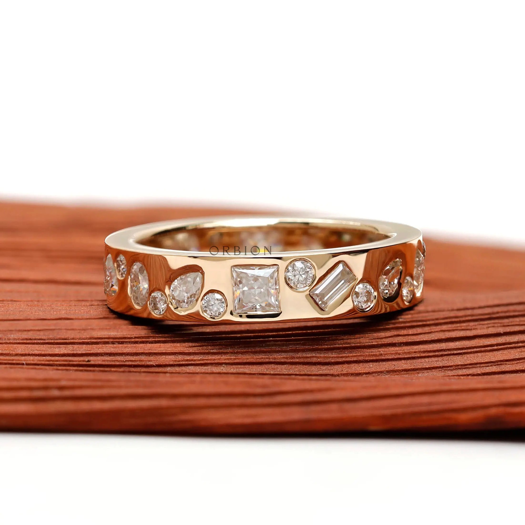 Low-profile mix-shape stone band shown angled on wooden surface.