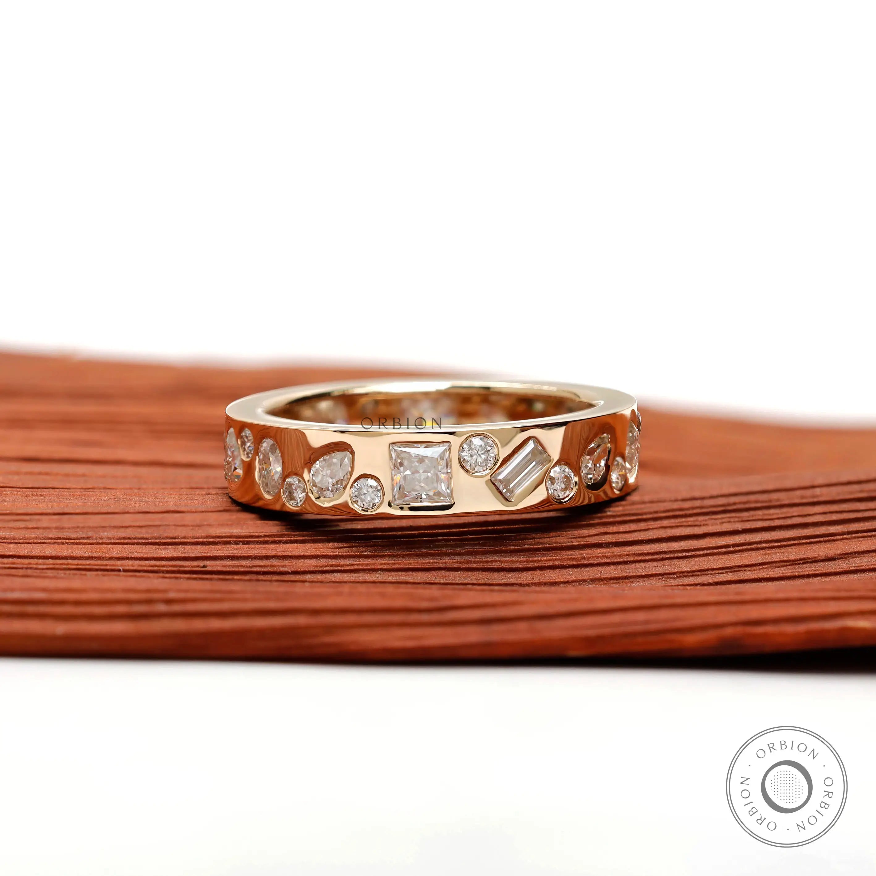 Low-profile mix-shape stone band shown angled on wooden surface.