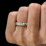 Close-up on finger showing mixed stones set in yellow gold band.