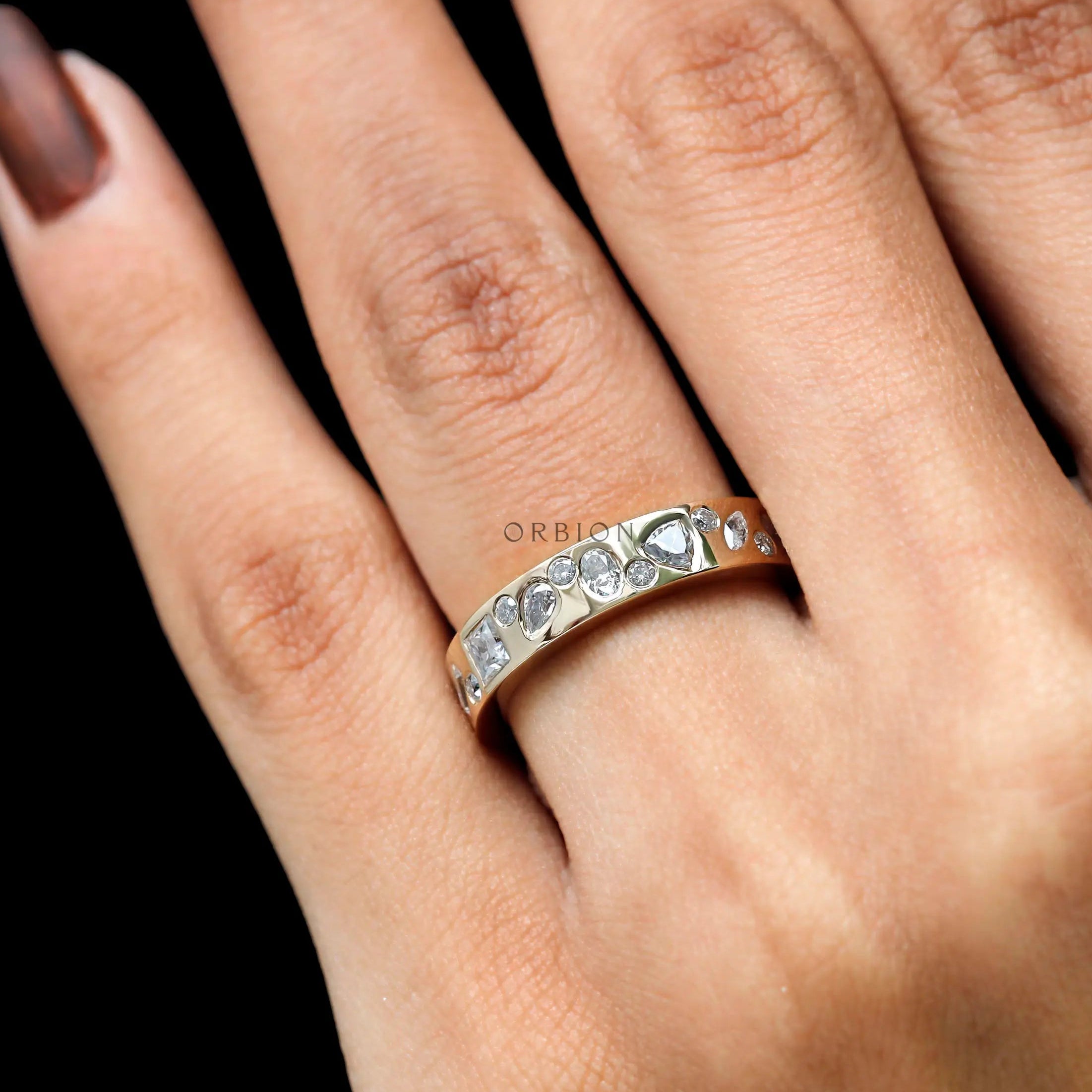 Angled on-hand shot showing sparkle and scattered stone arrangement.