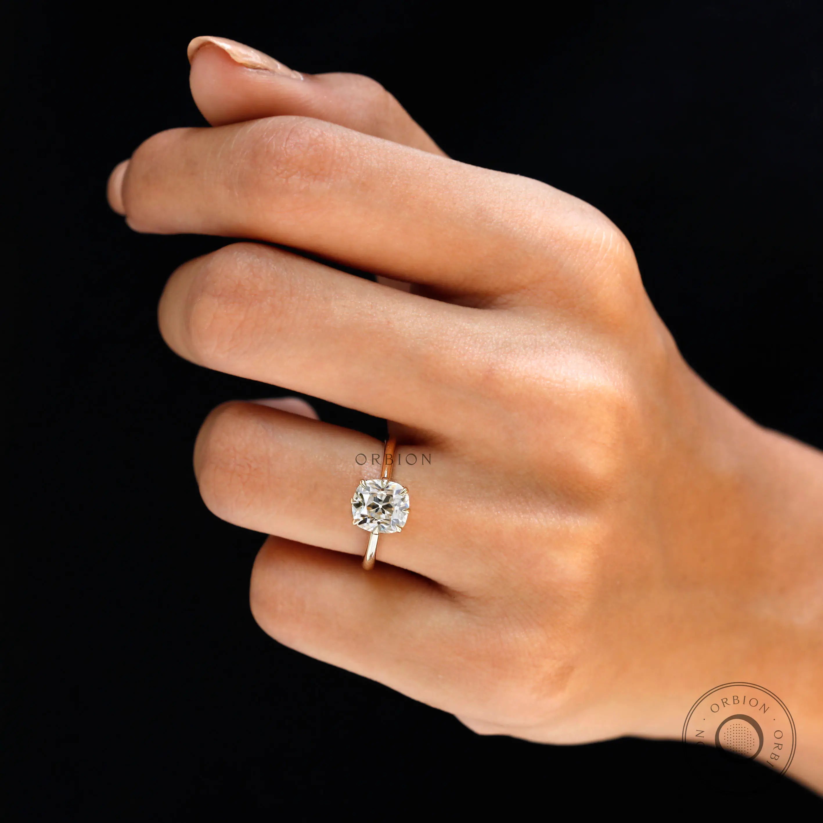 Yellow gold solitaire engagement ring with elongated cushion diamond on hand