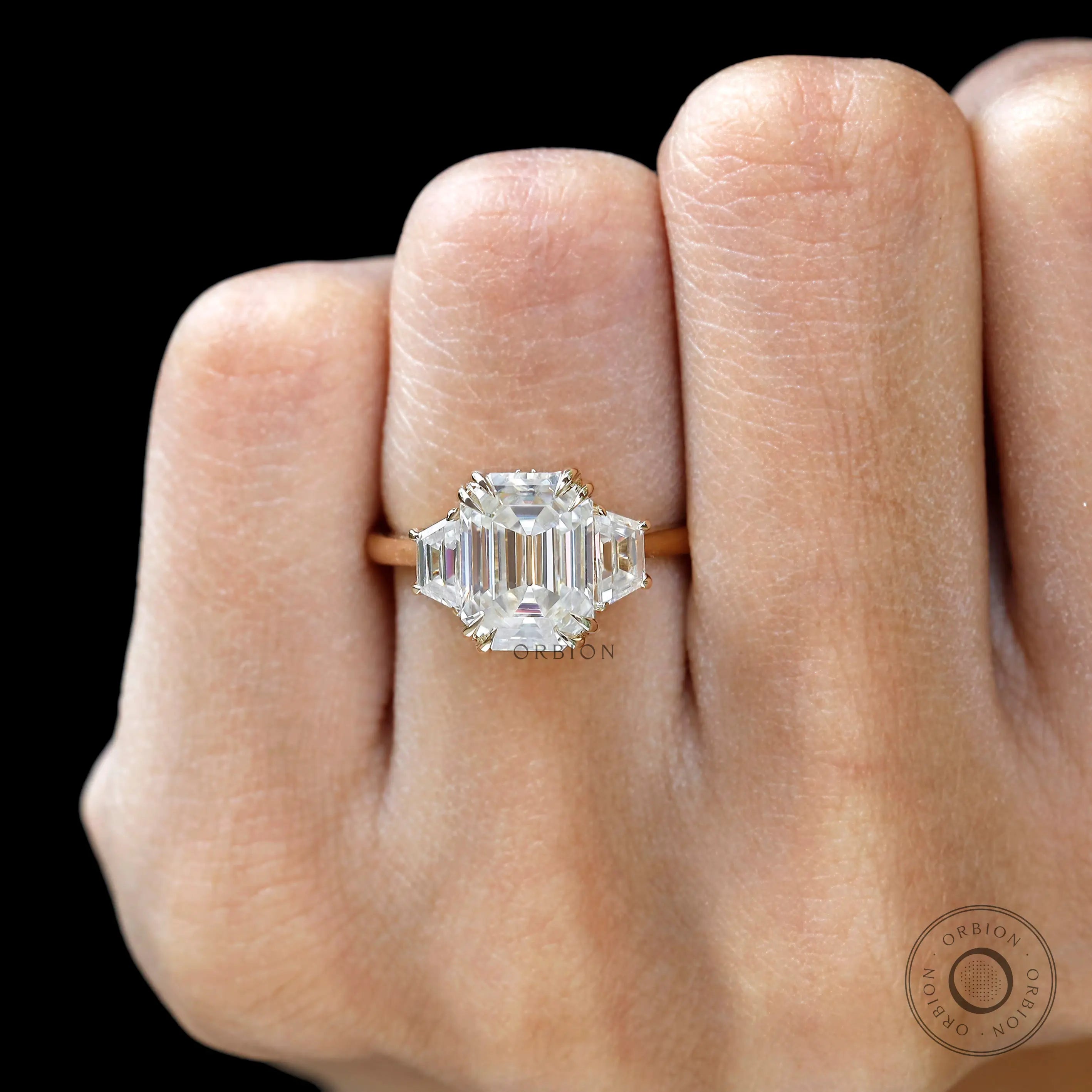 Emerald cut ring with trapezoid and round side stones close up