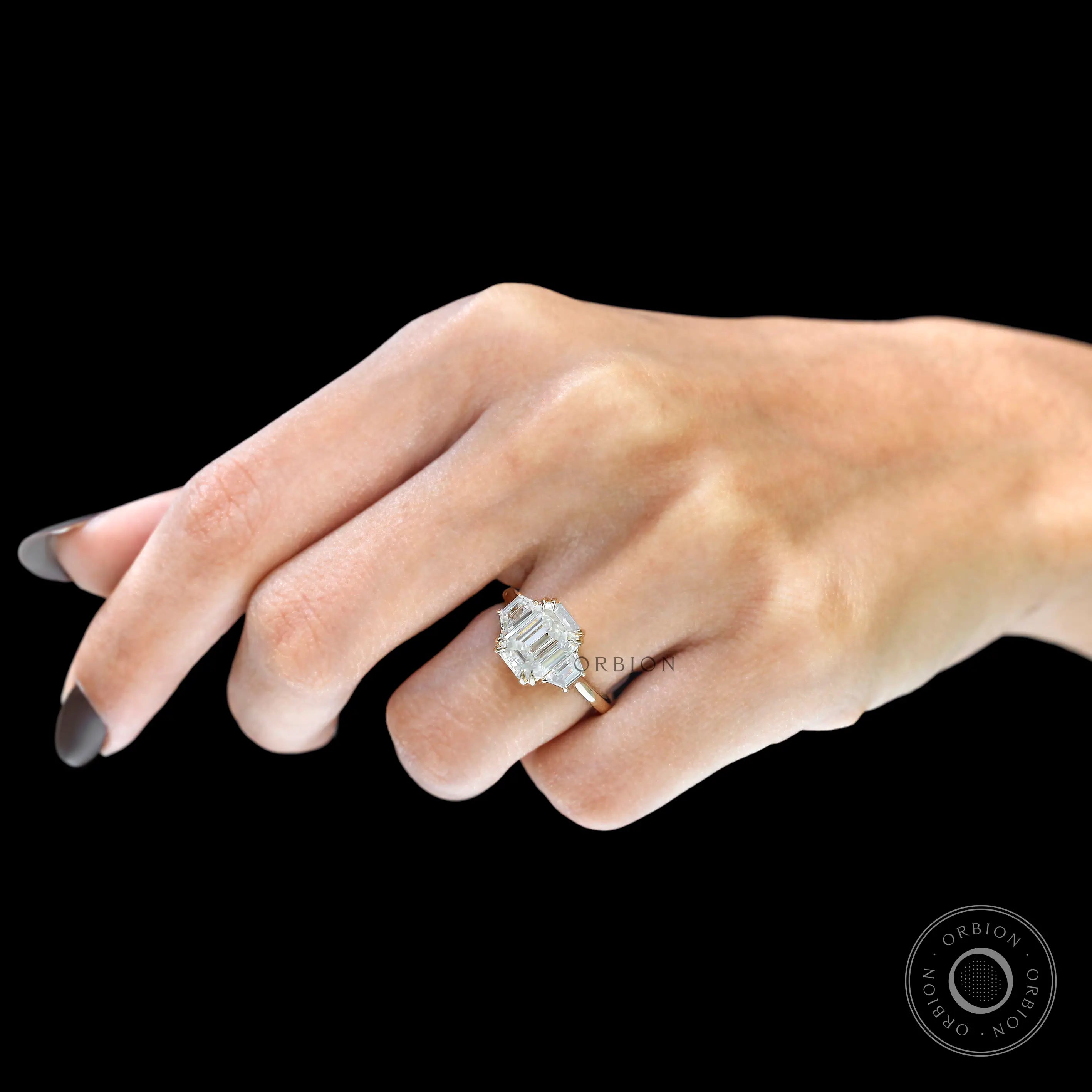 Emerald cut ring with trapezoid and round side stones close up
