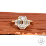 Emerald cut three stone cathedral engagement ring in 14K yellow gold