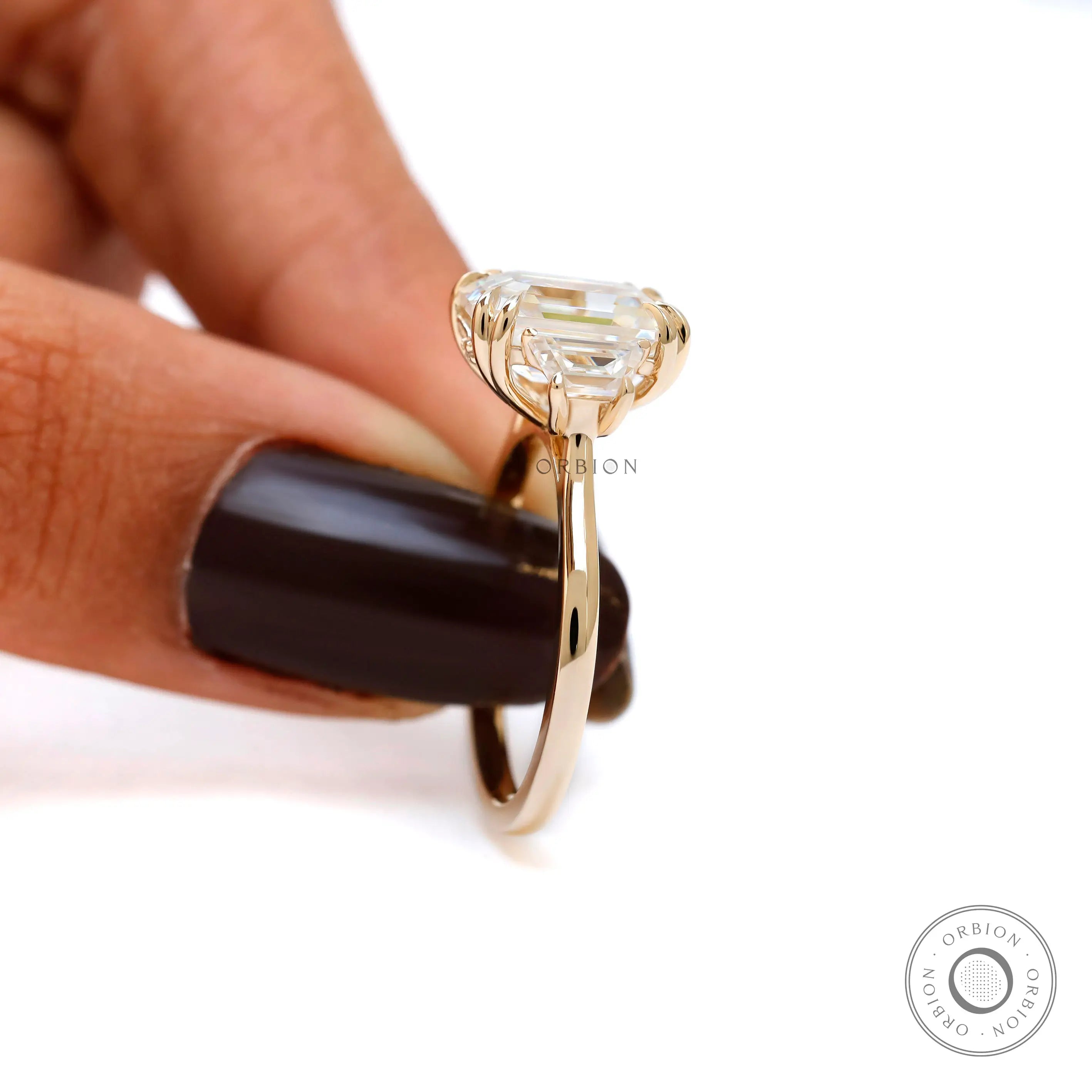 Step cut emerald three stone engagement ring elegant pose