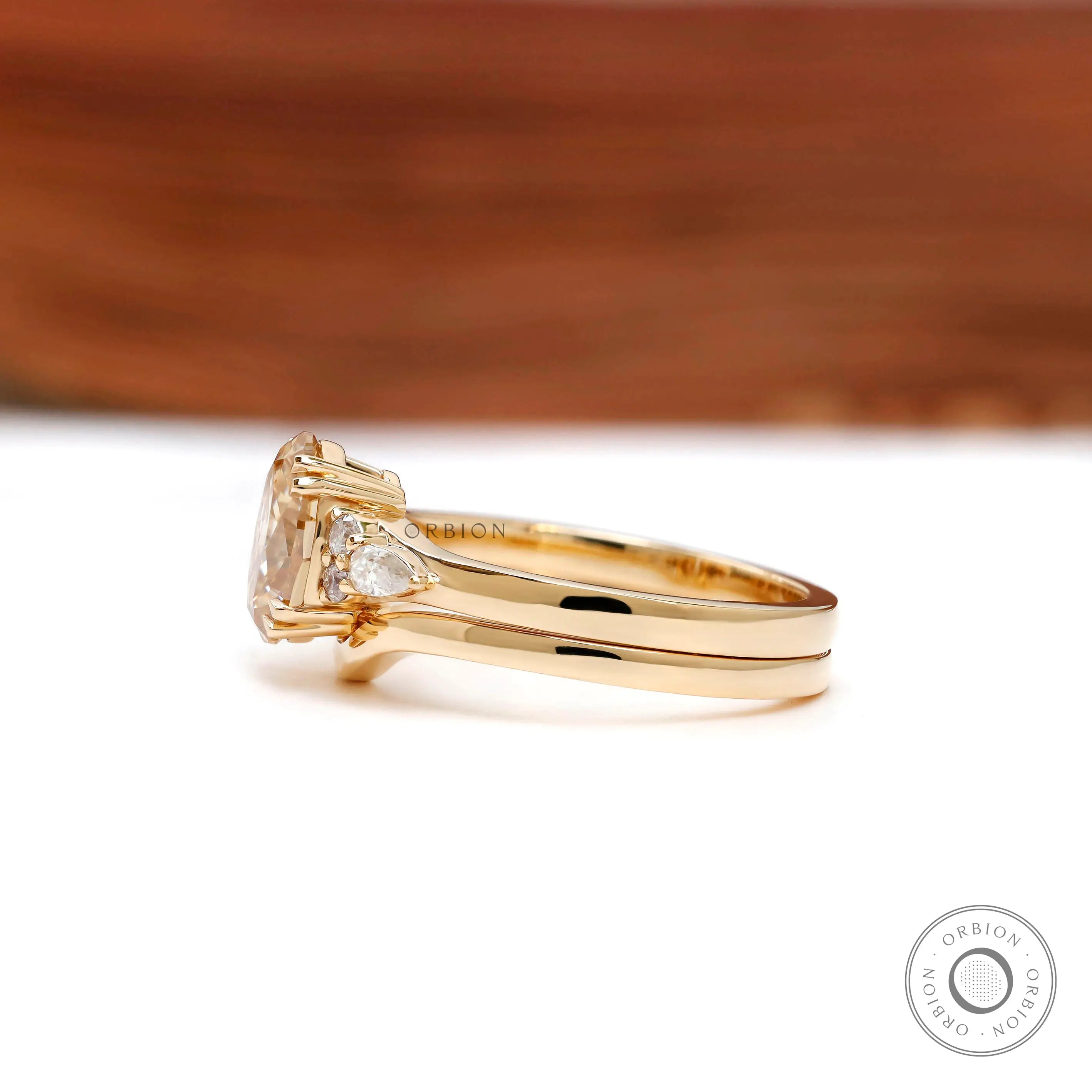 Pear and round accent stones on yellow gold bridal ring set side profile  