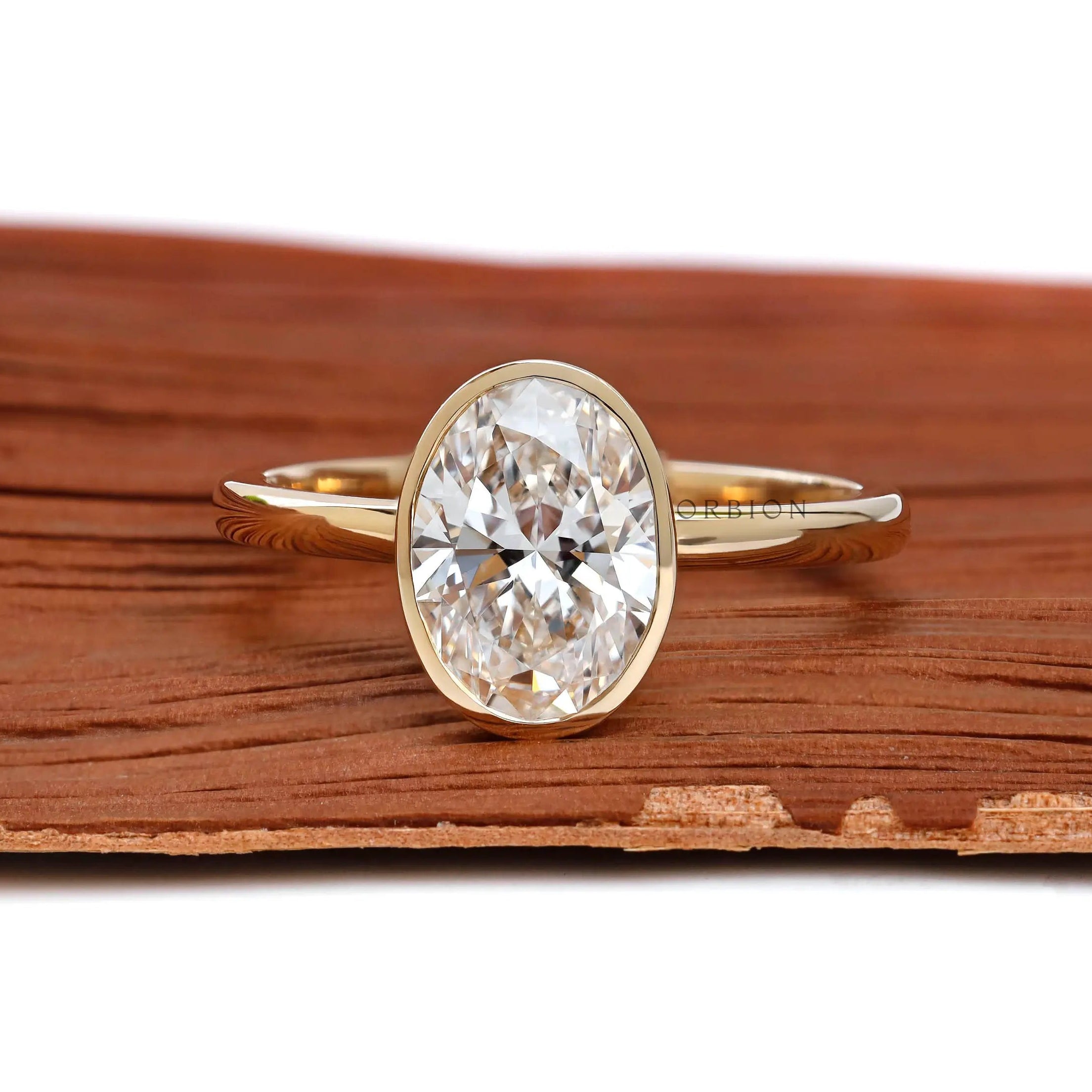 Oval cut bezel set lab diamond engagement ring in 14k yellow gold front view