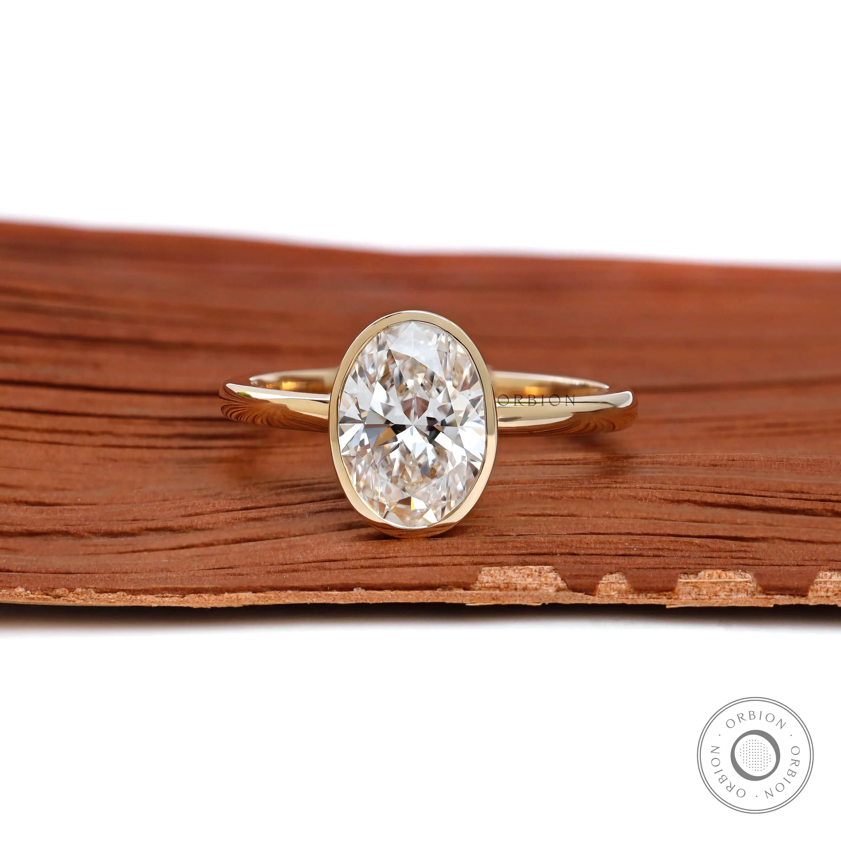 Oval cut bezel set lab diamond engagement ring in 14k yellow gold front view