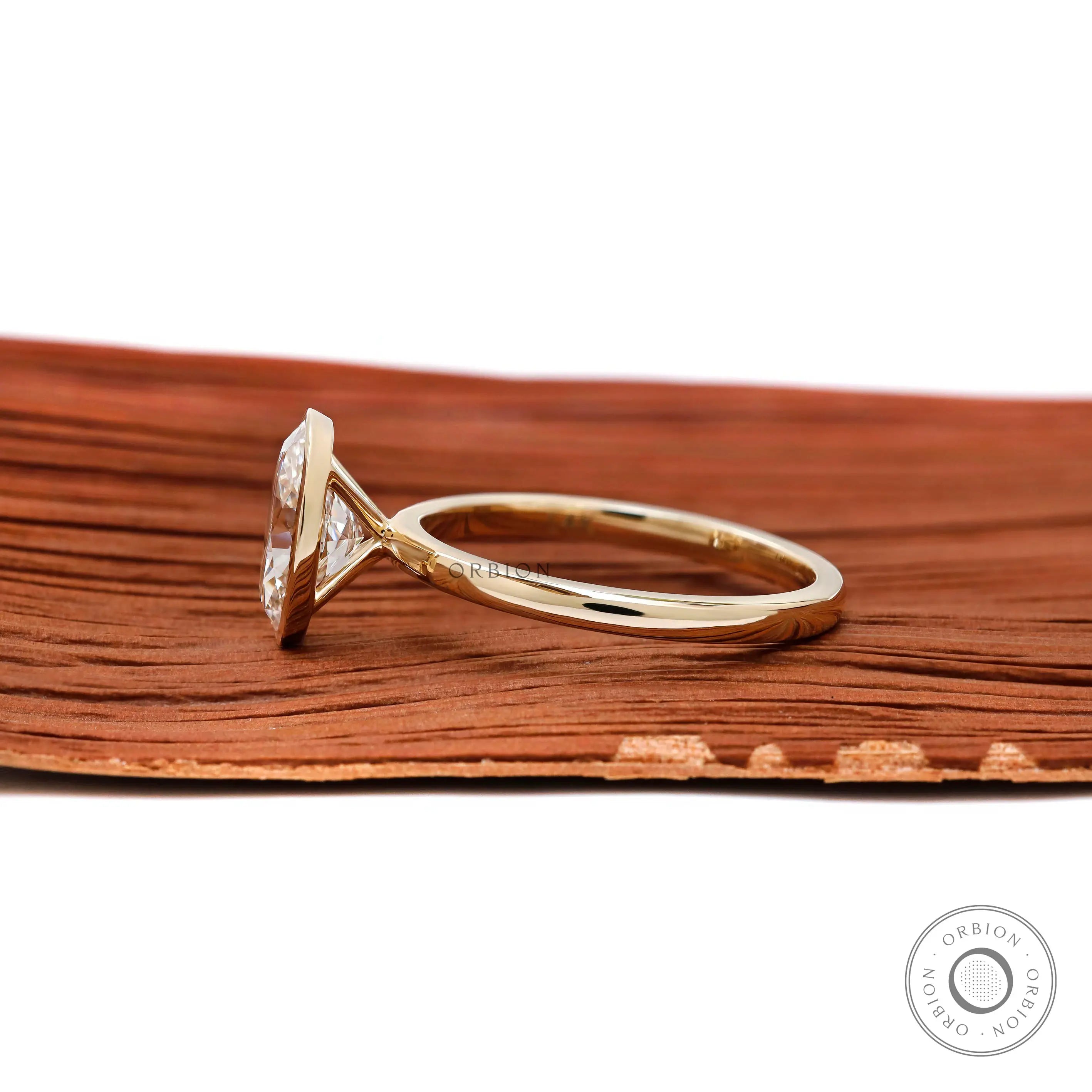 Modern bezel set oval diamond ring on wooden background  