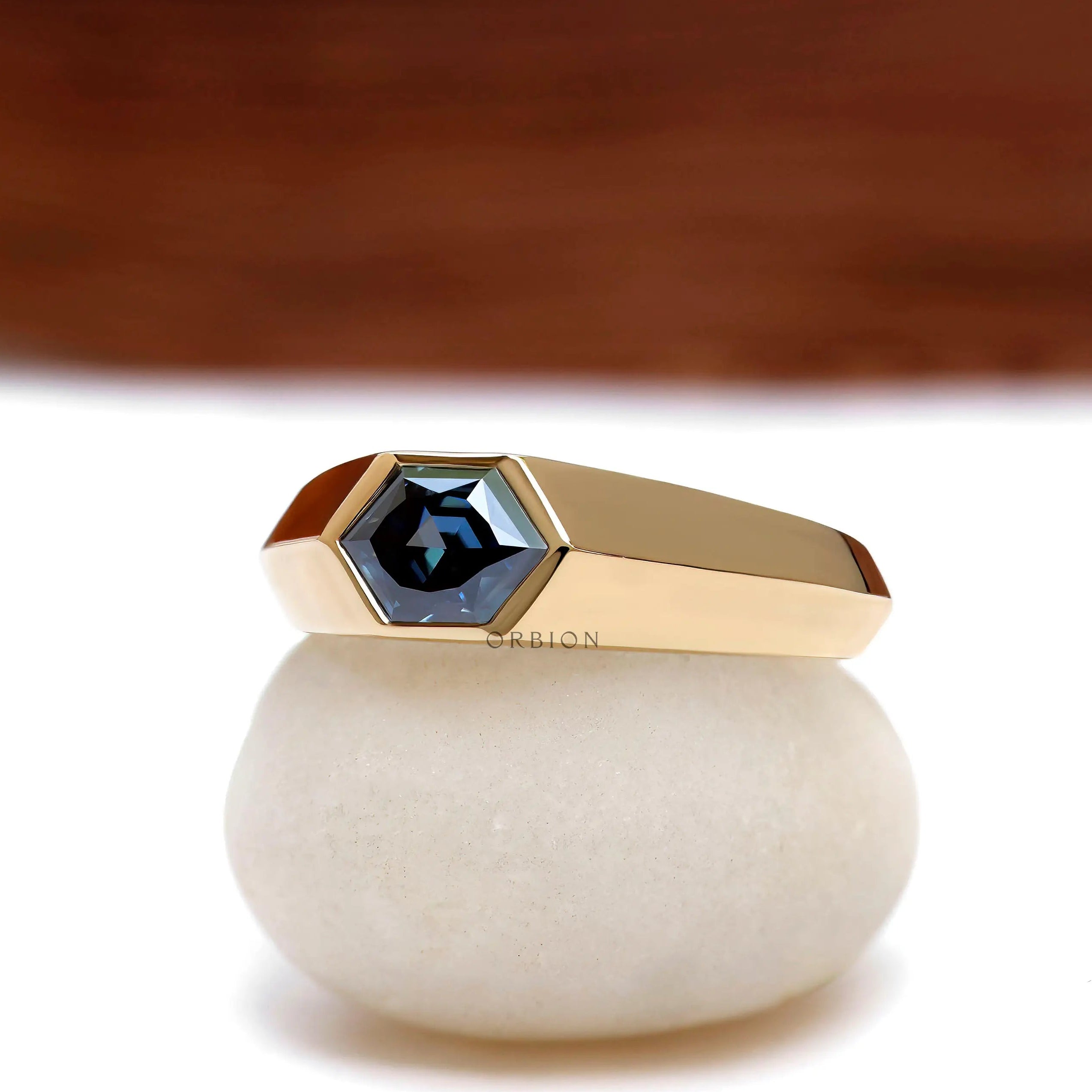 Close up of deep blue moissanite in modern yellow gold signet ring