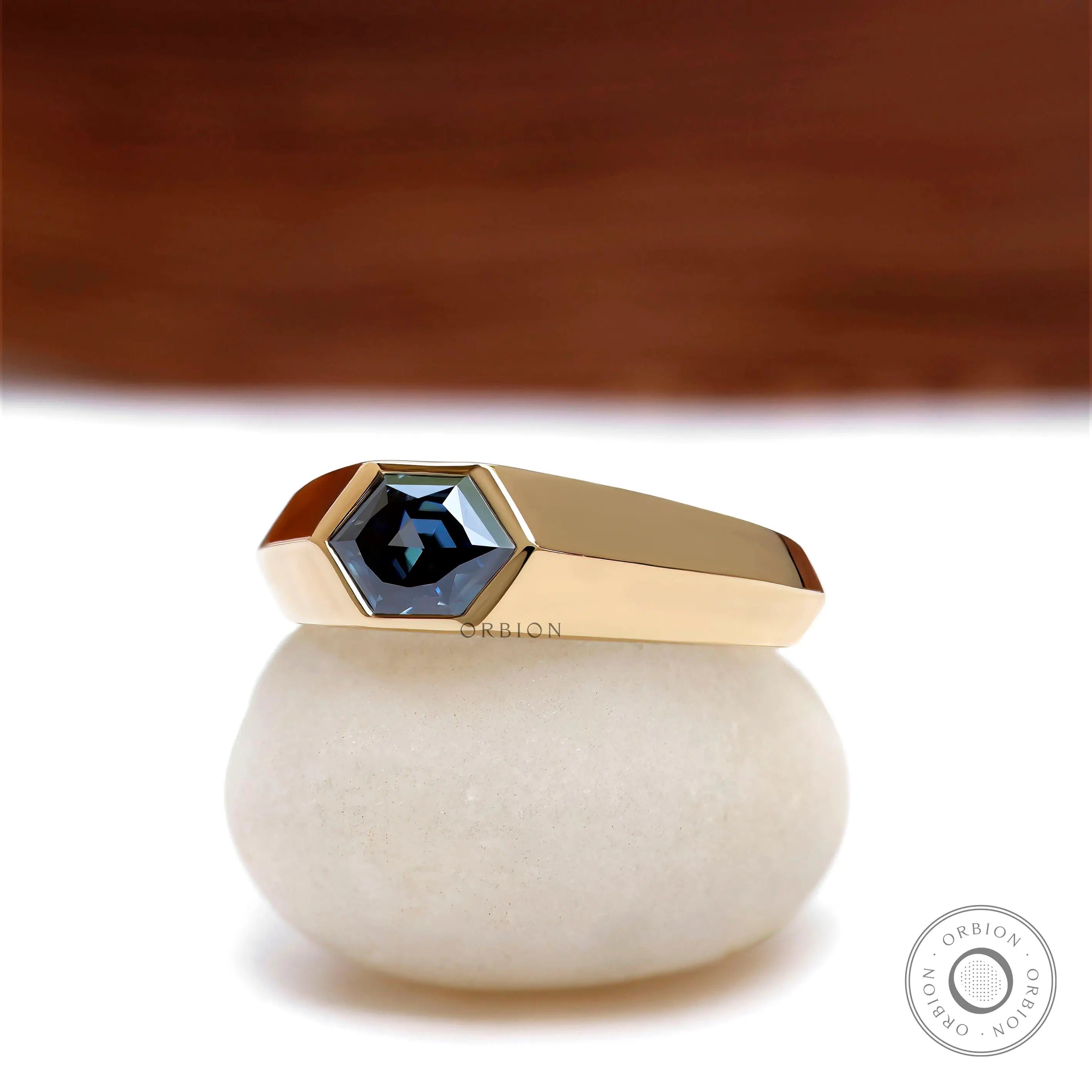 Close up of deep blue moissanite in modern yellow gold signet ring