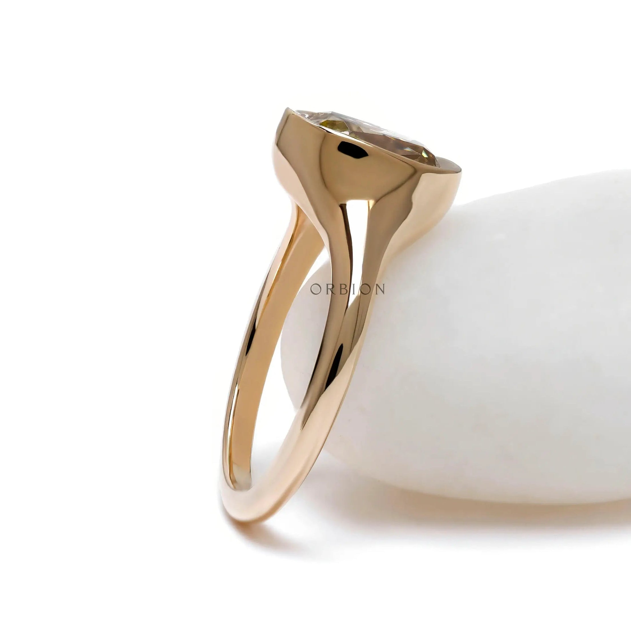 Side view of bezel set cushion champagne moissanite in yellow gold