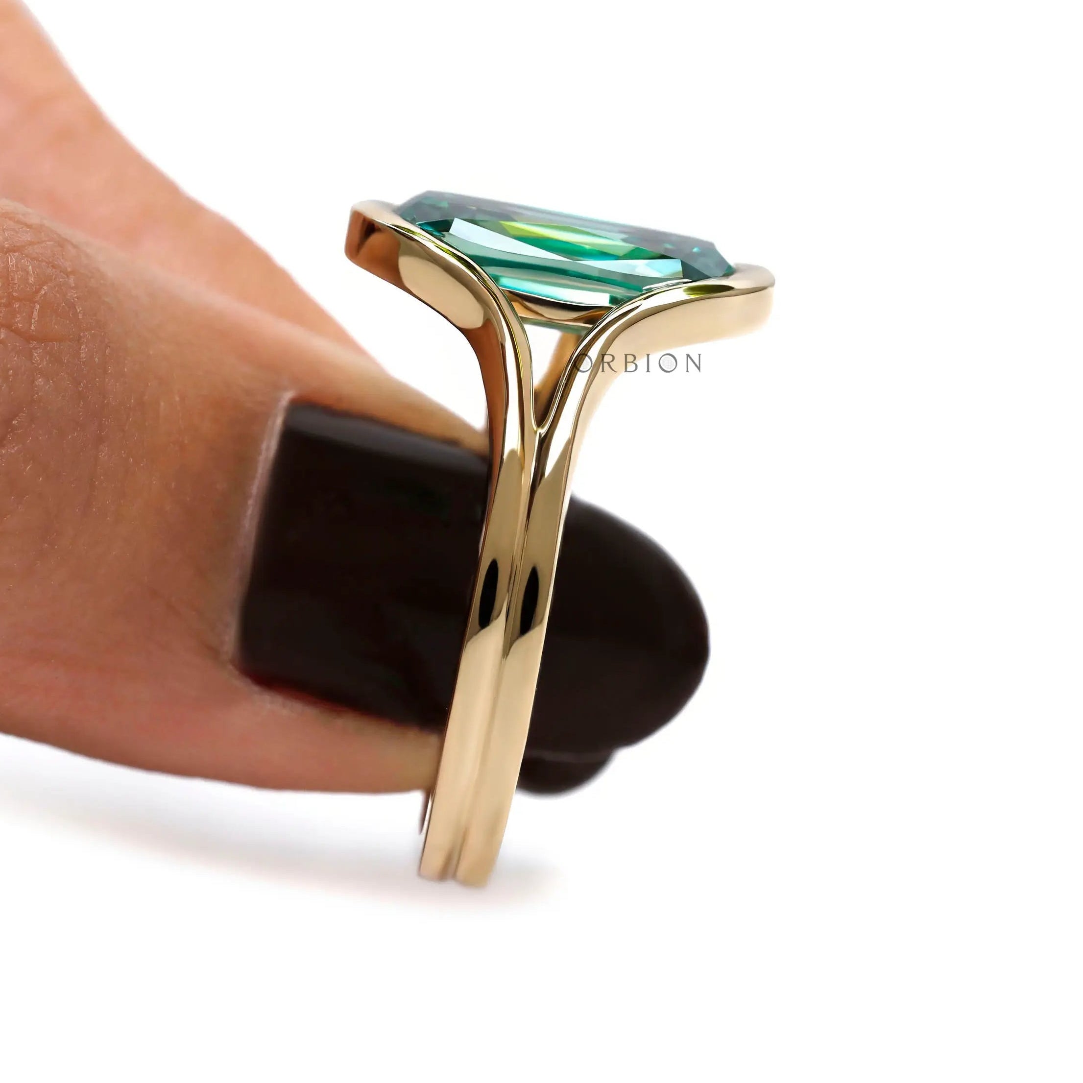 Side close-up of green moissanite floating bezel ring held