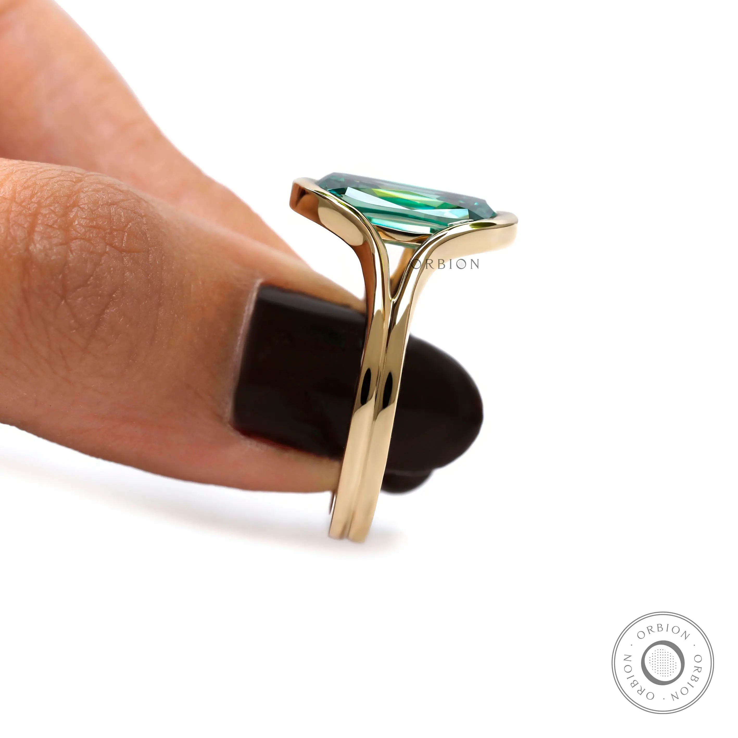Side close-up of green moissanite floating bezel ring held