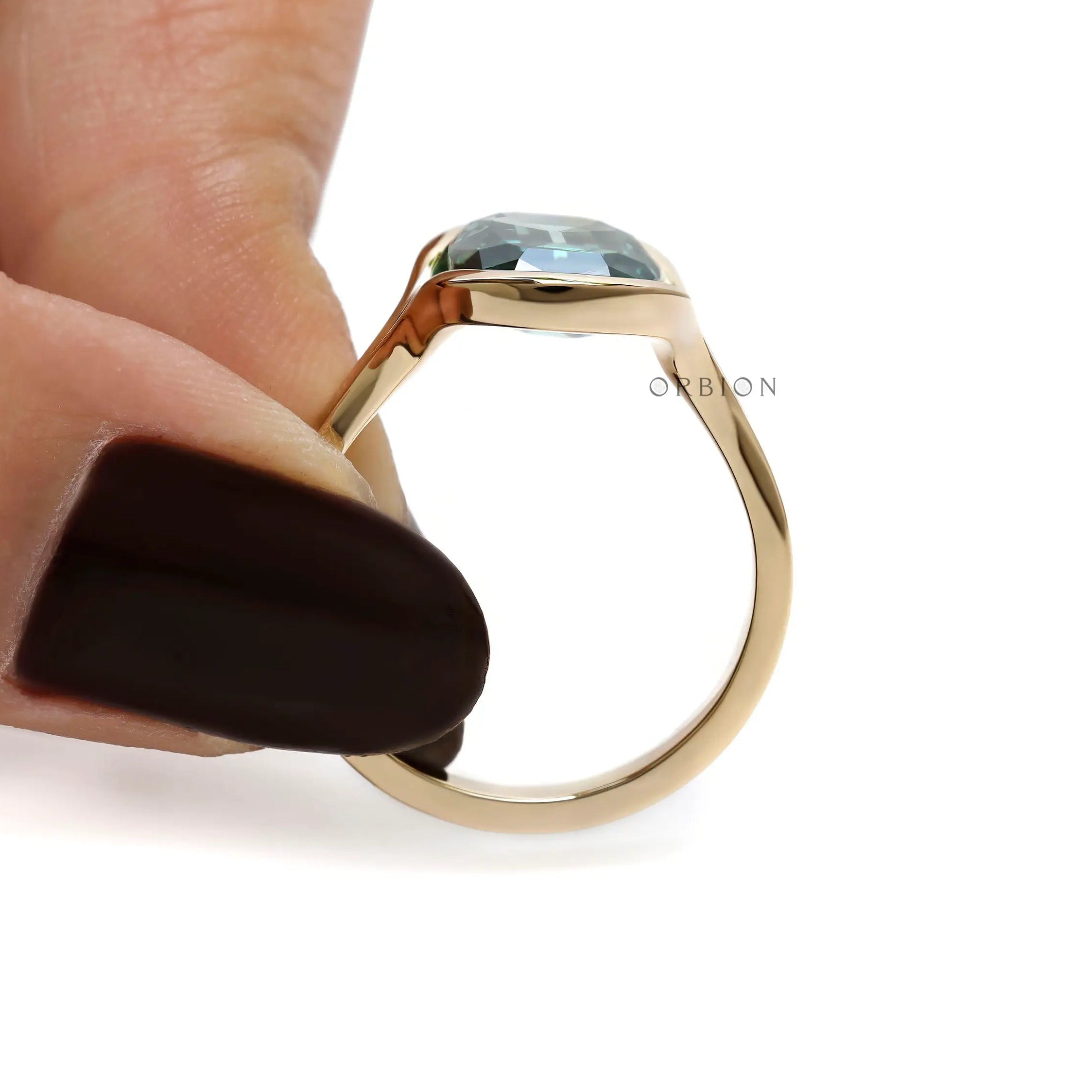 Side profile of elongated green moissanite ring held by hand