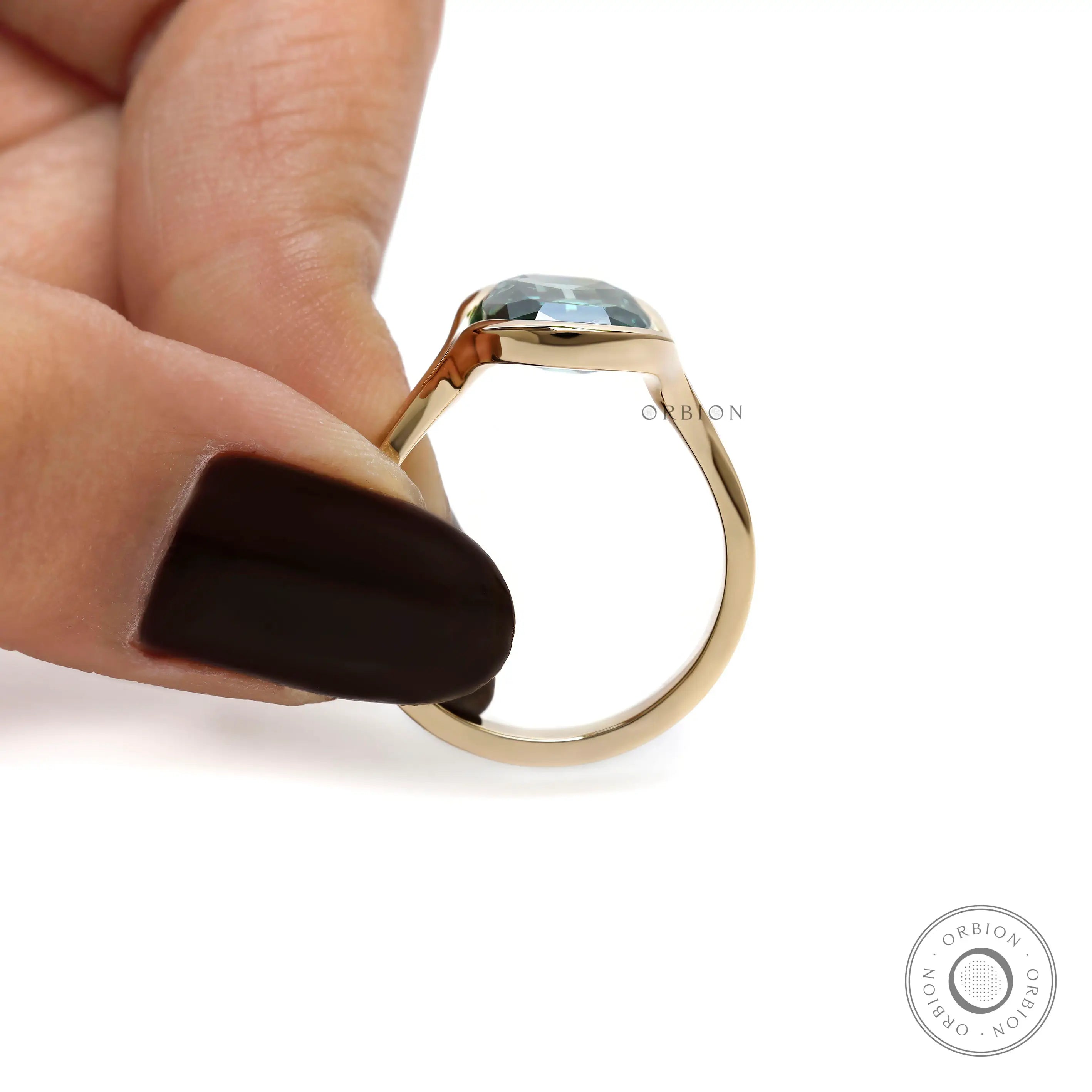 Side profile of elongated green moissanite ring held by hand