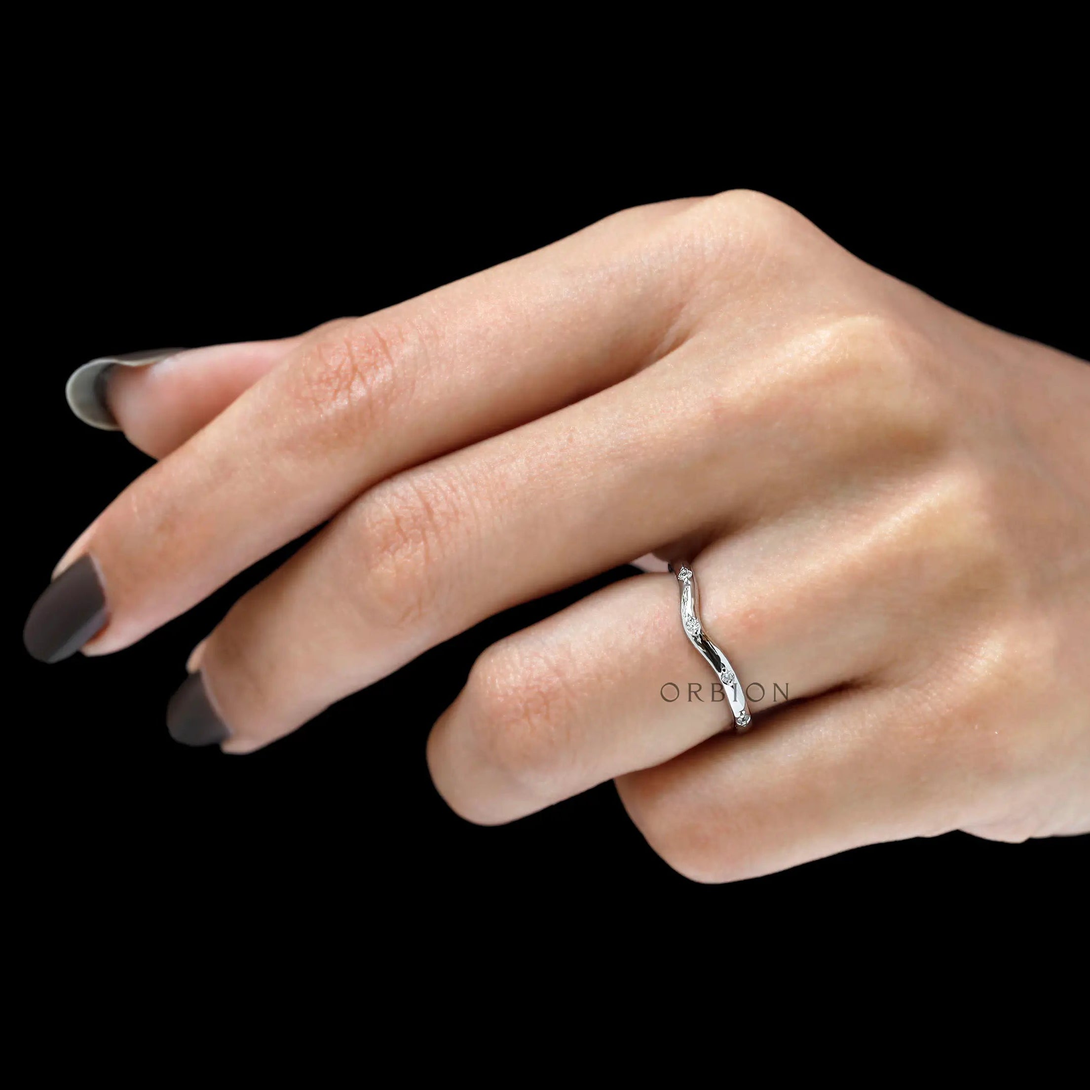Minimalist curved diamond ring worn on finger