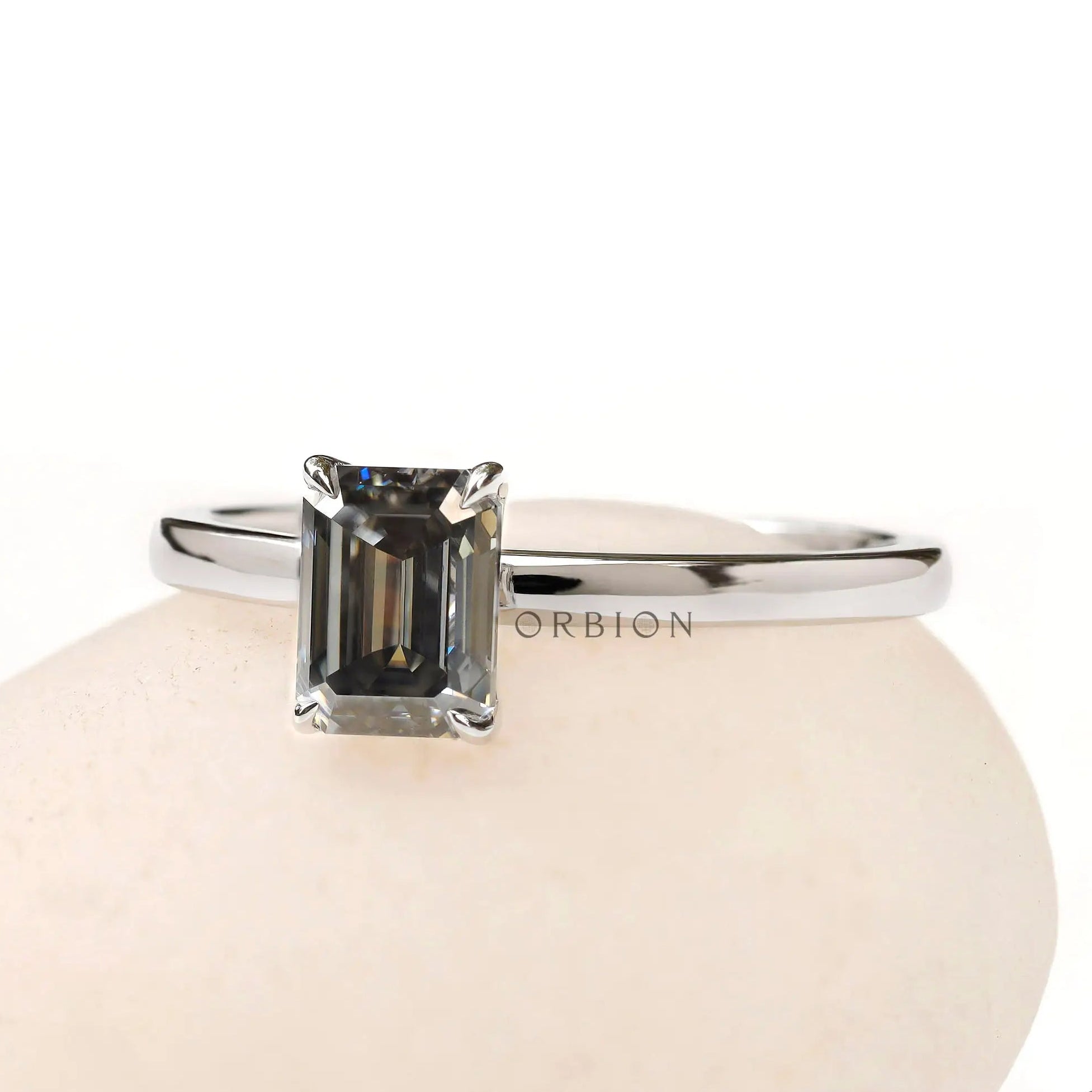 Angled front view emerald cut grey moissanite solitaire ring