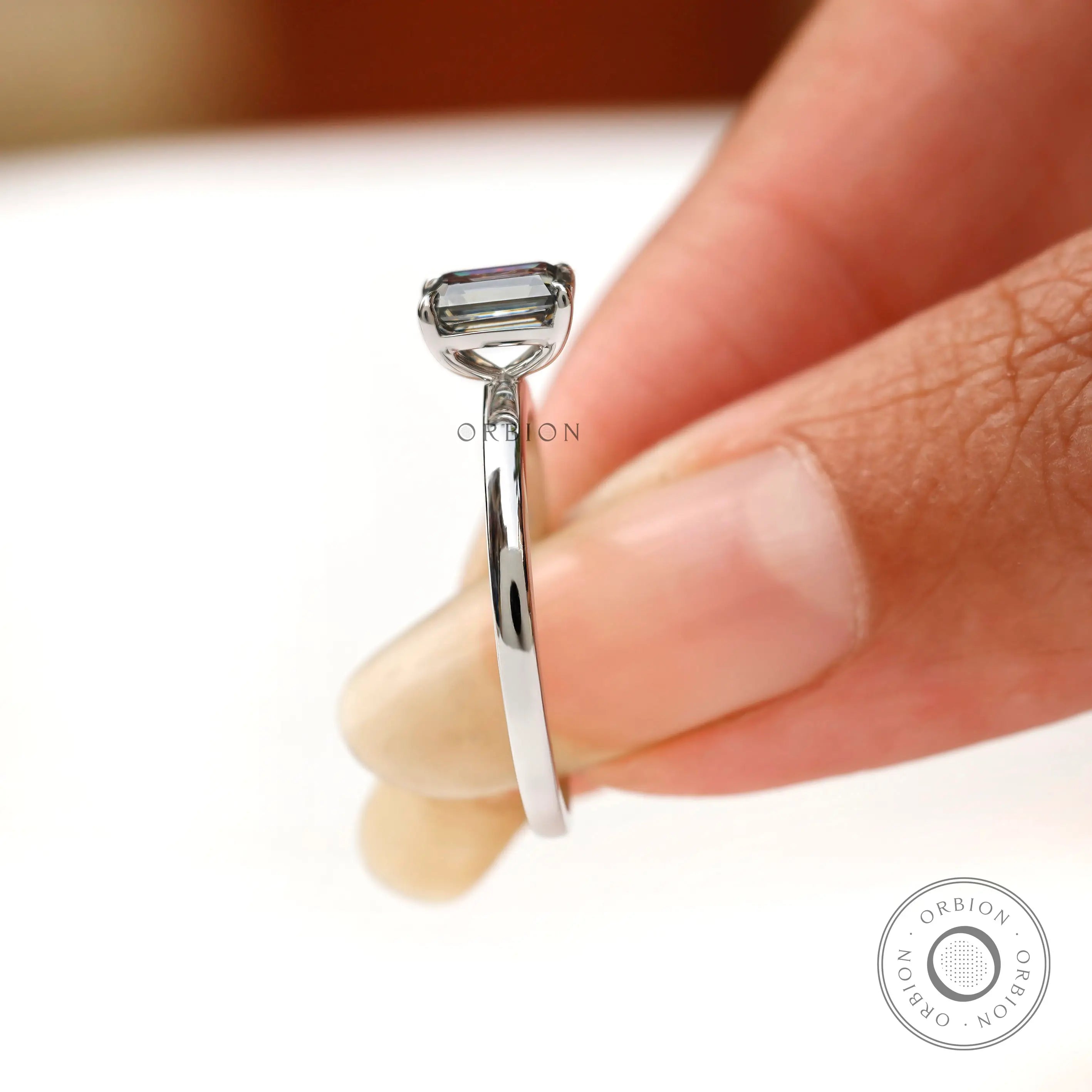On hand side view emerald cut grey moissanite solitaire