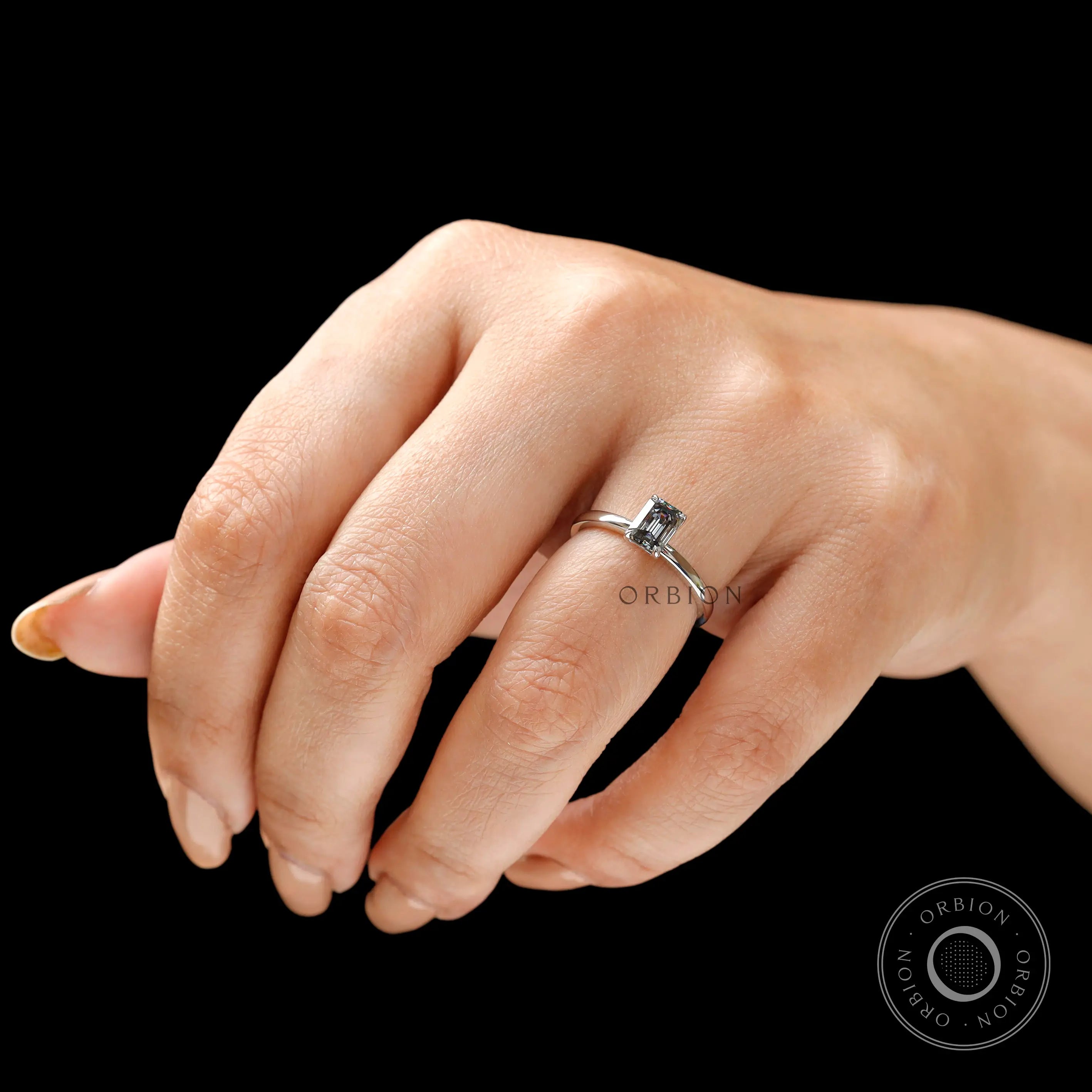 On hand angled view emerald cut grey moissanite solitaire