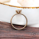 Slim band yellow gold solitaire ring on wooden surface