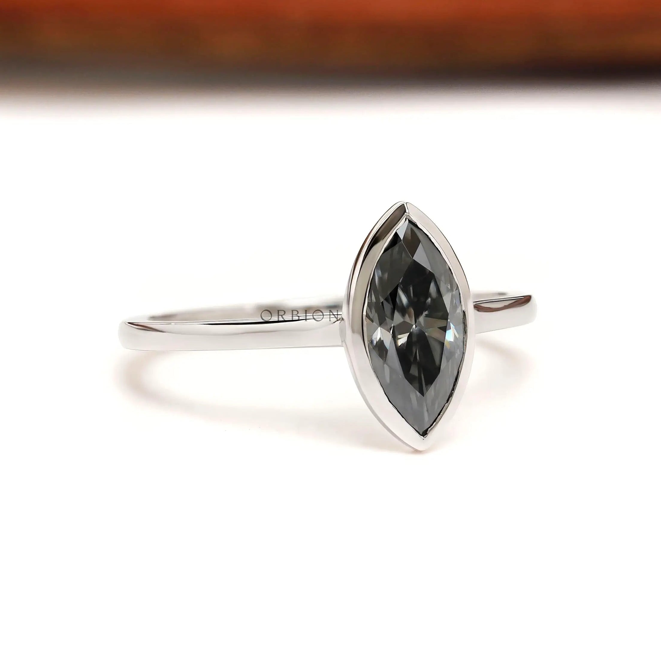 Side profile of marquise moissanite bezel ring with slim white gold band