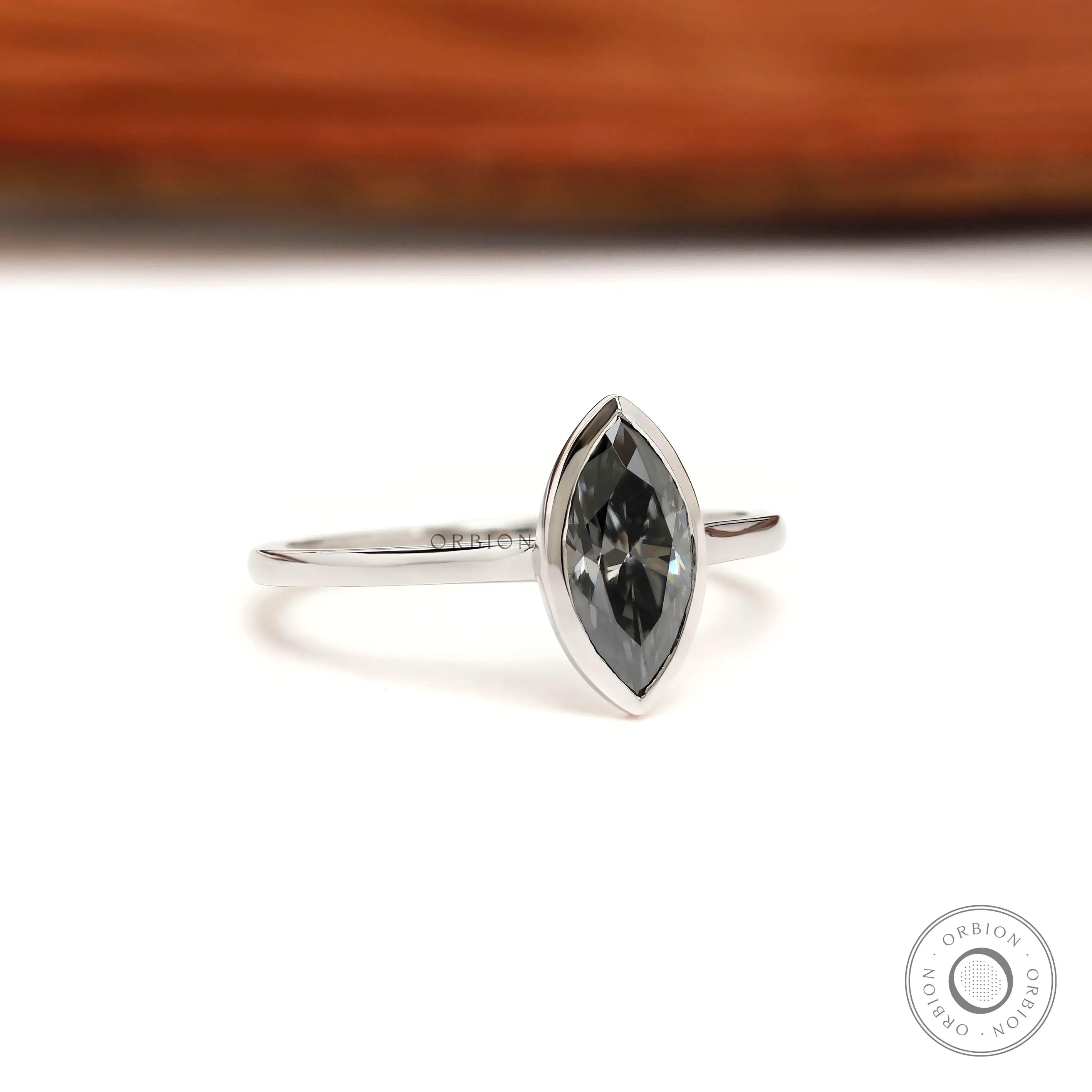 Side profile of marquise moissanite bezel ring with slim white gold band