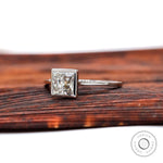 Angled view of princess cut bezel set diamond ring on wooden surface