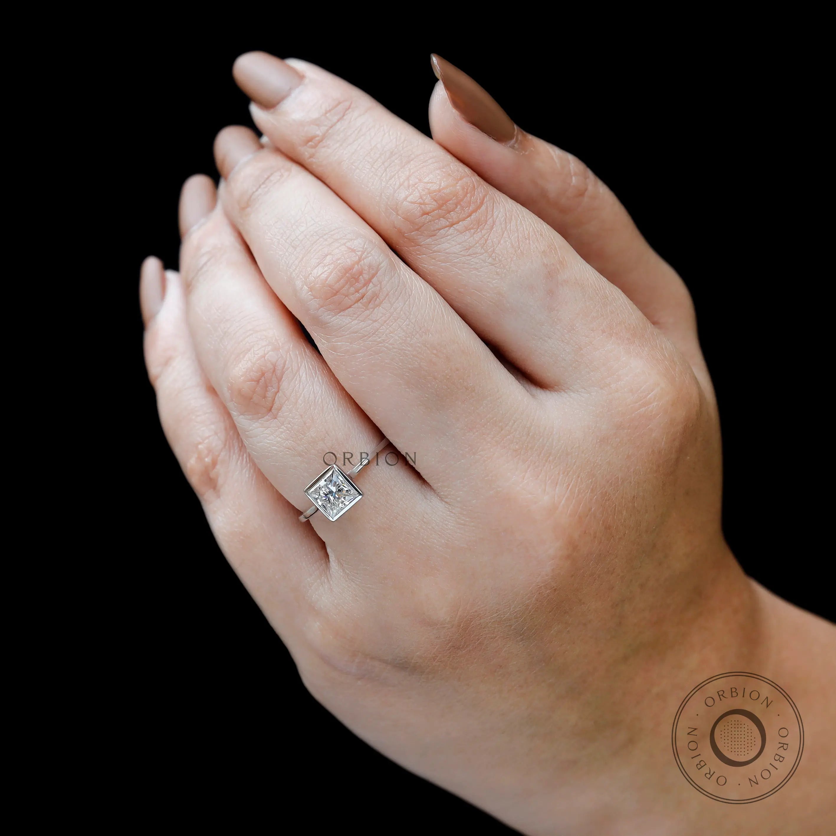 Princess cut lab grown diamond ring worn on hand against black background