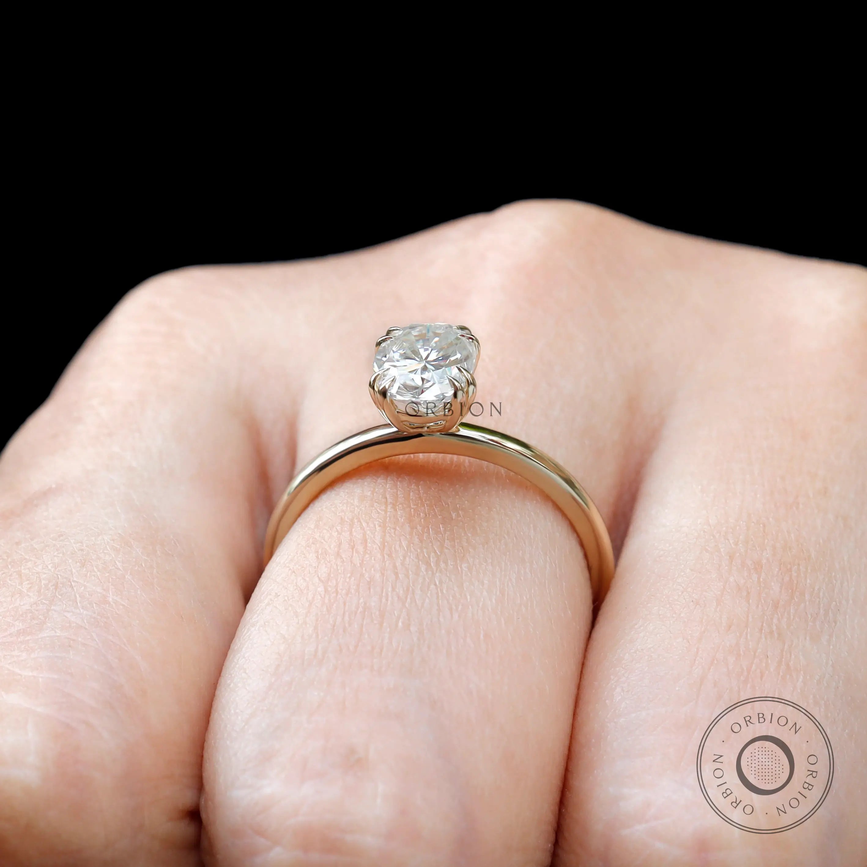 Oval moissanite solitaire ring in yellow gold on hand
