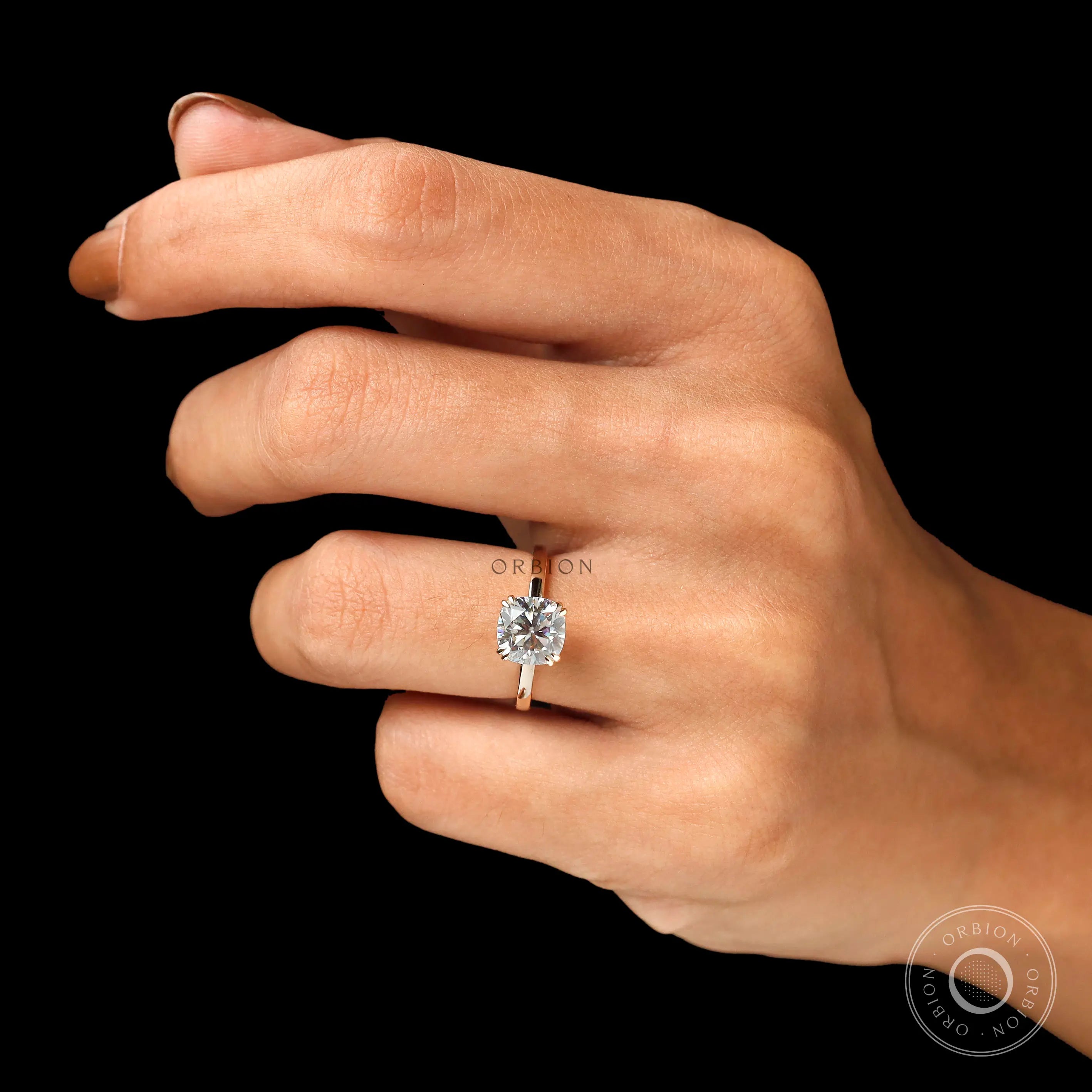 Cushion cut solitaire engagement ring in 14K yellow gold on fingure