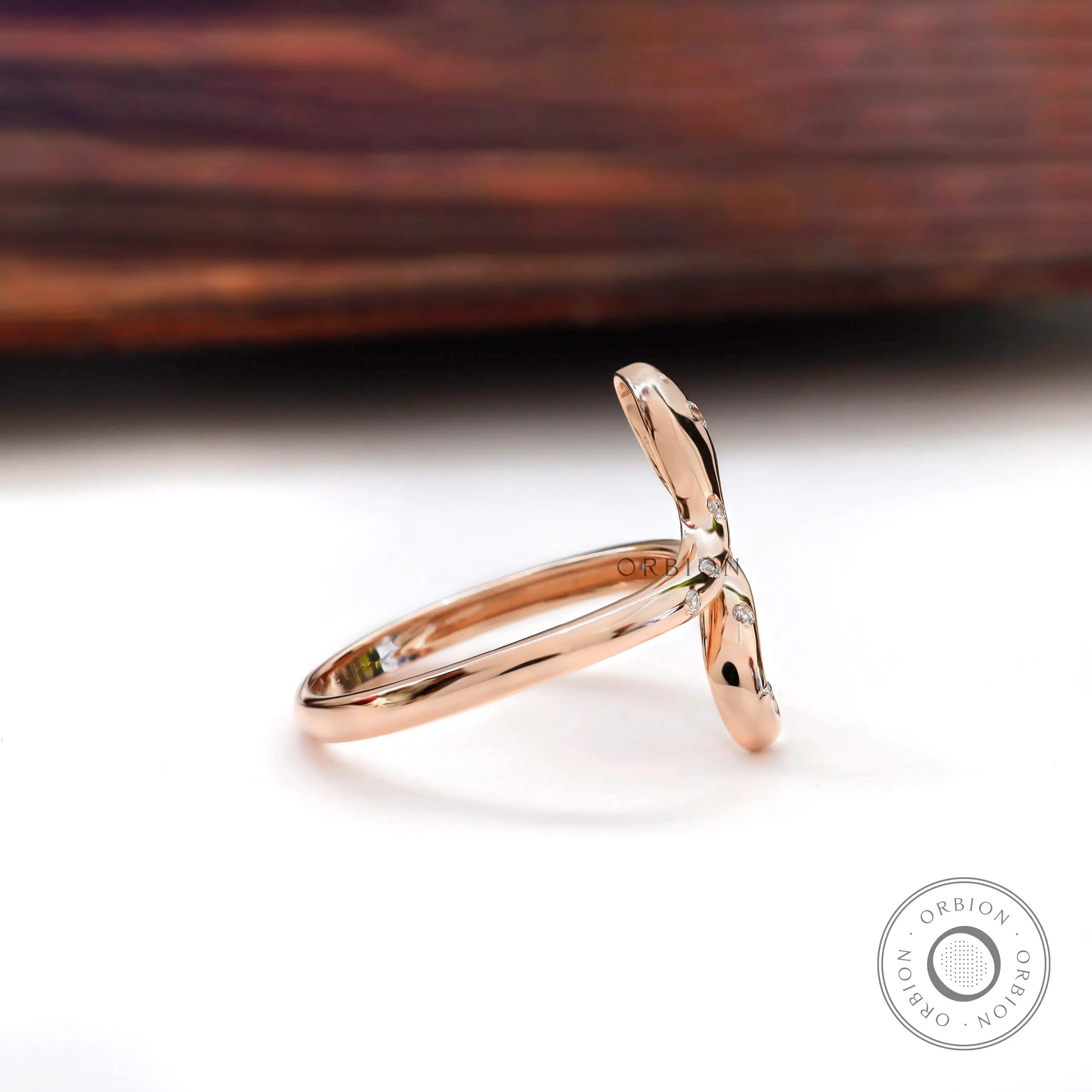 Side profile of rose gold snake ring with diamond accents