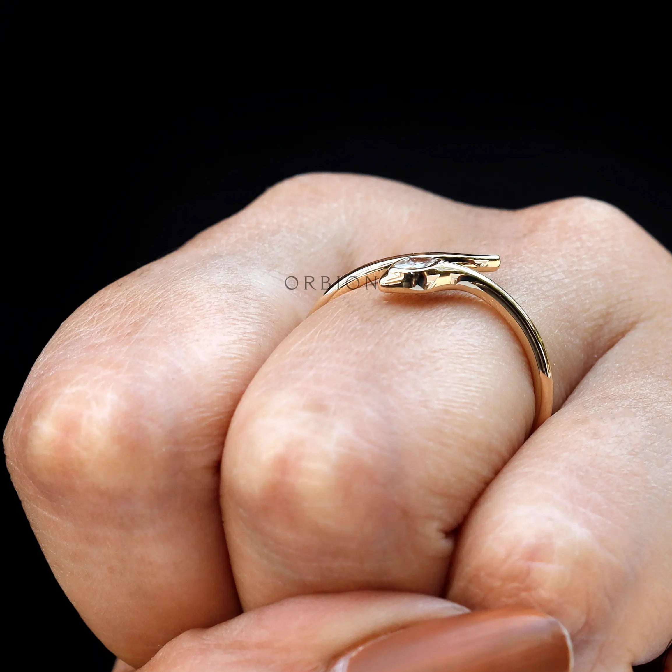 Minimalist gold snake ring photographed on finger