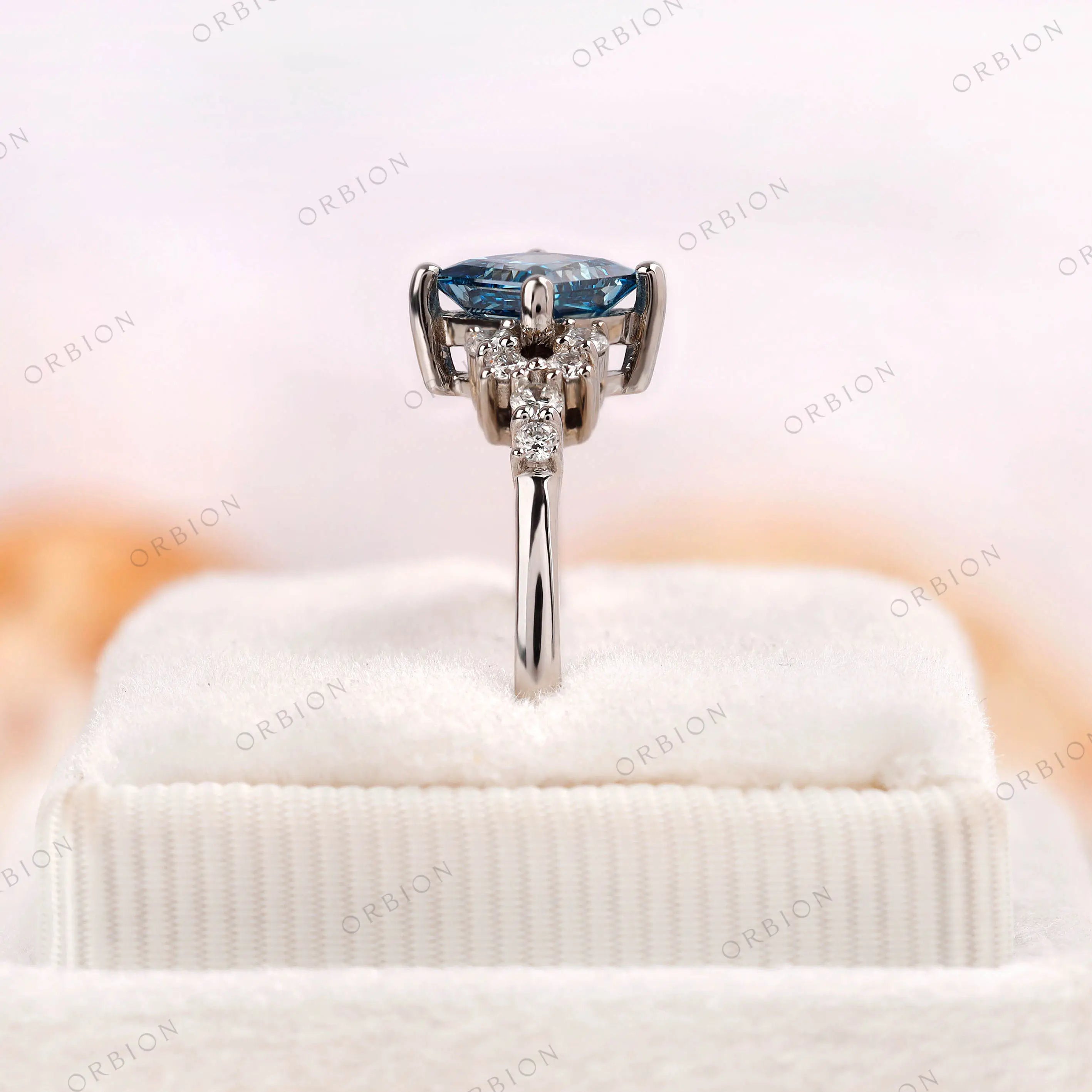 Cluster style engagement ring with blue princess cut diamond and moissanite accents
