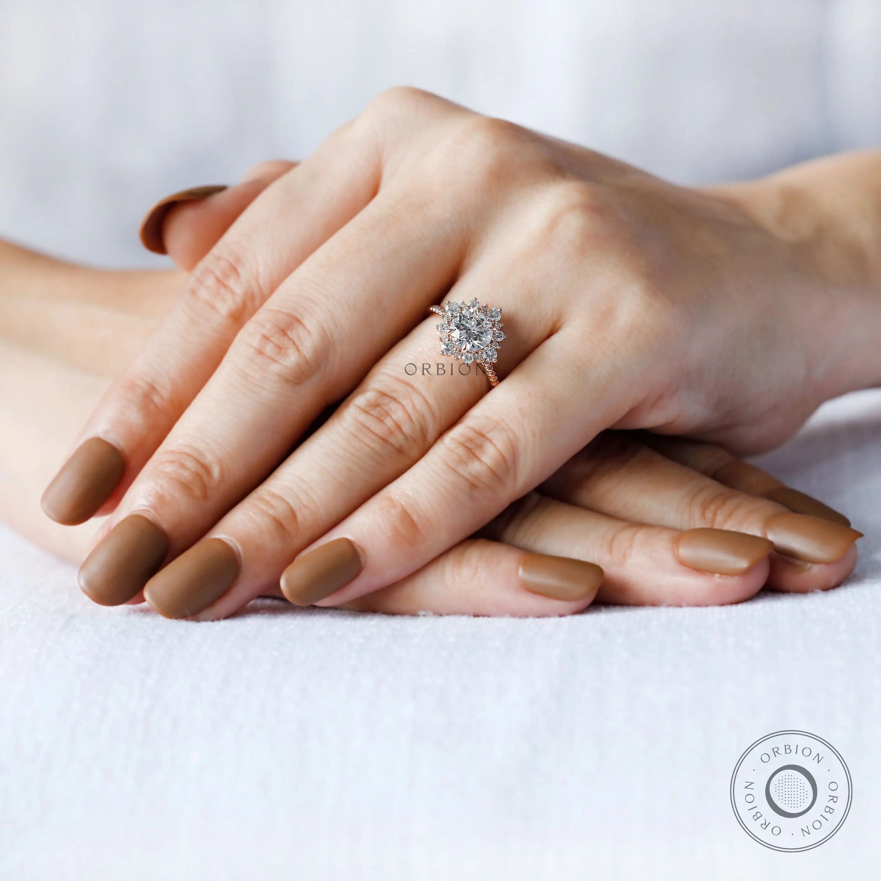On-hand view of round halo engagement ring in rose gold