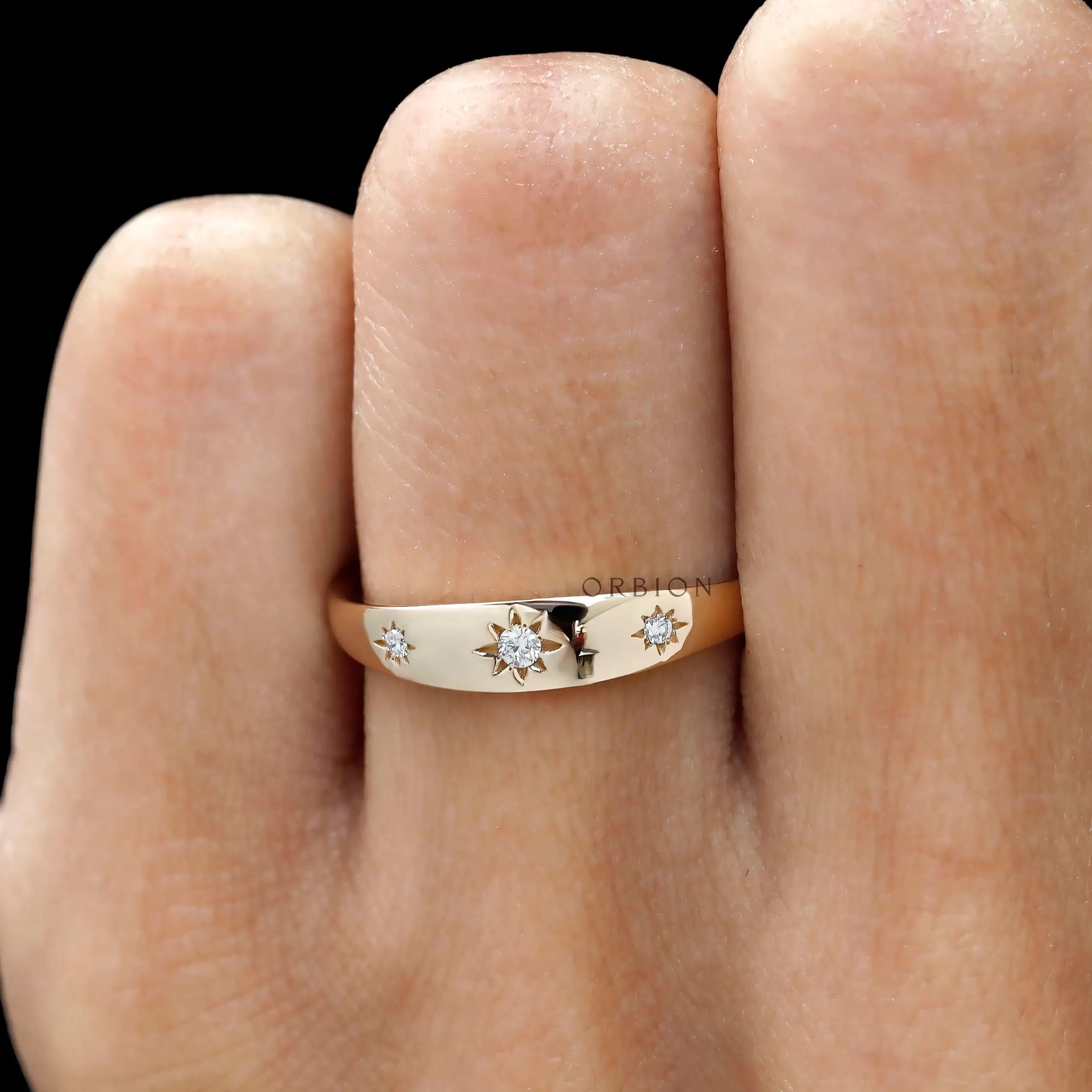 Front worn view of yellow gold band featuring three starburst diamonds.