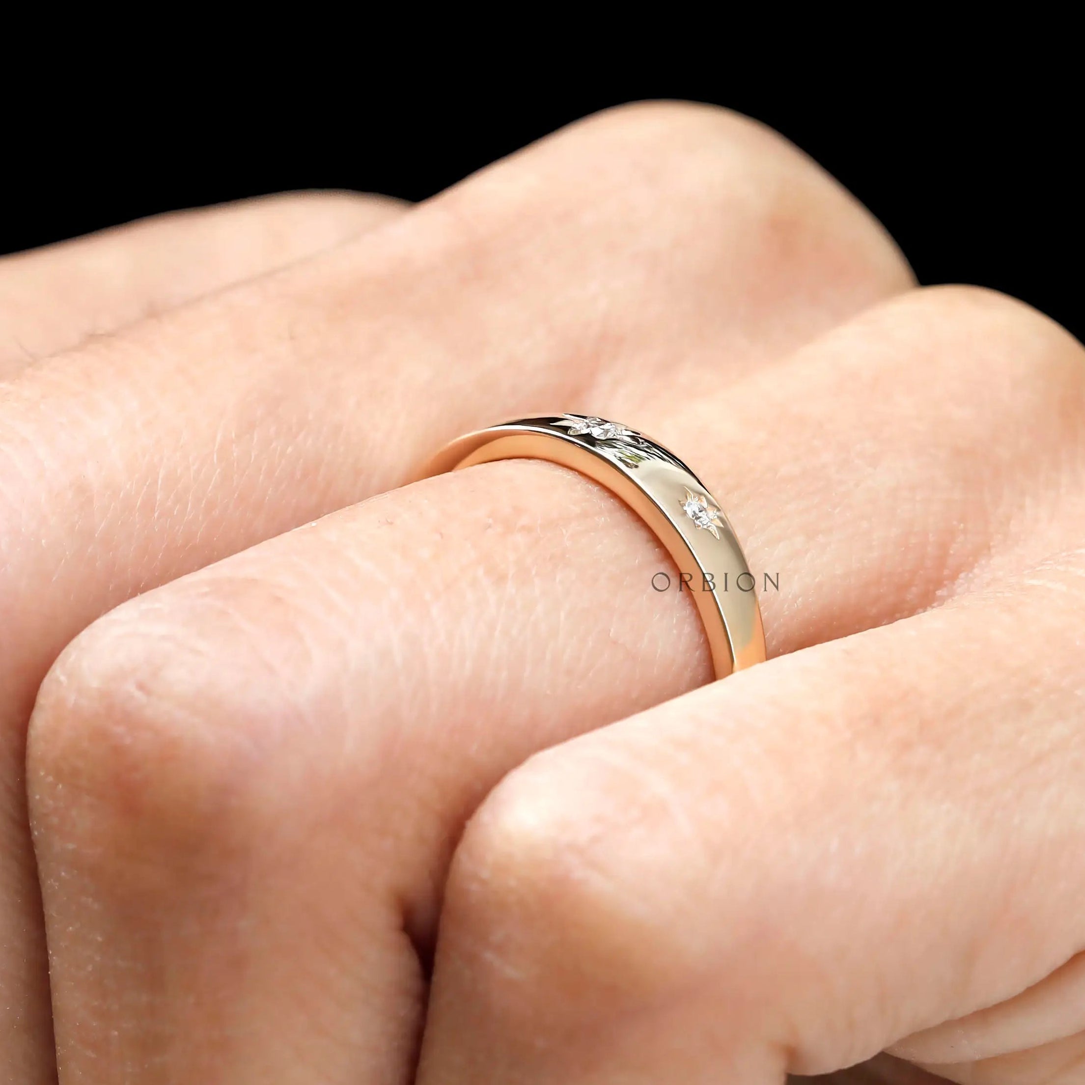Close up of yellow gold band with starburst set diamonds.