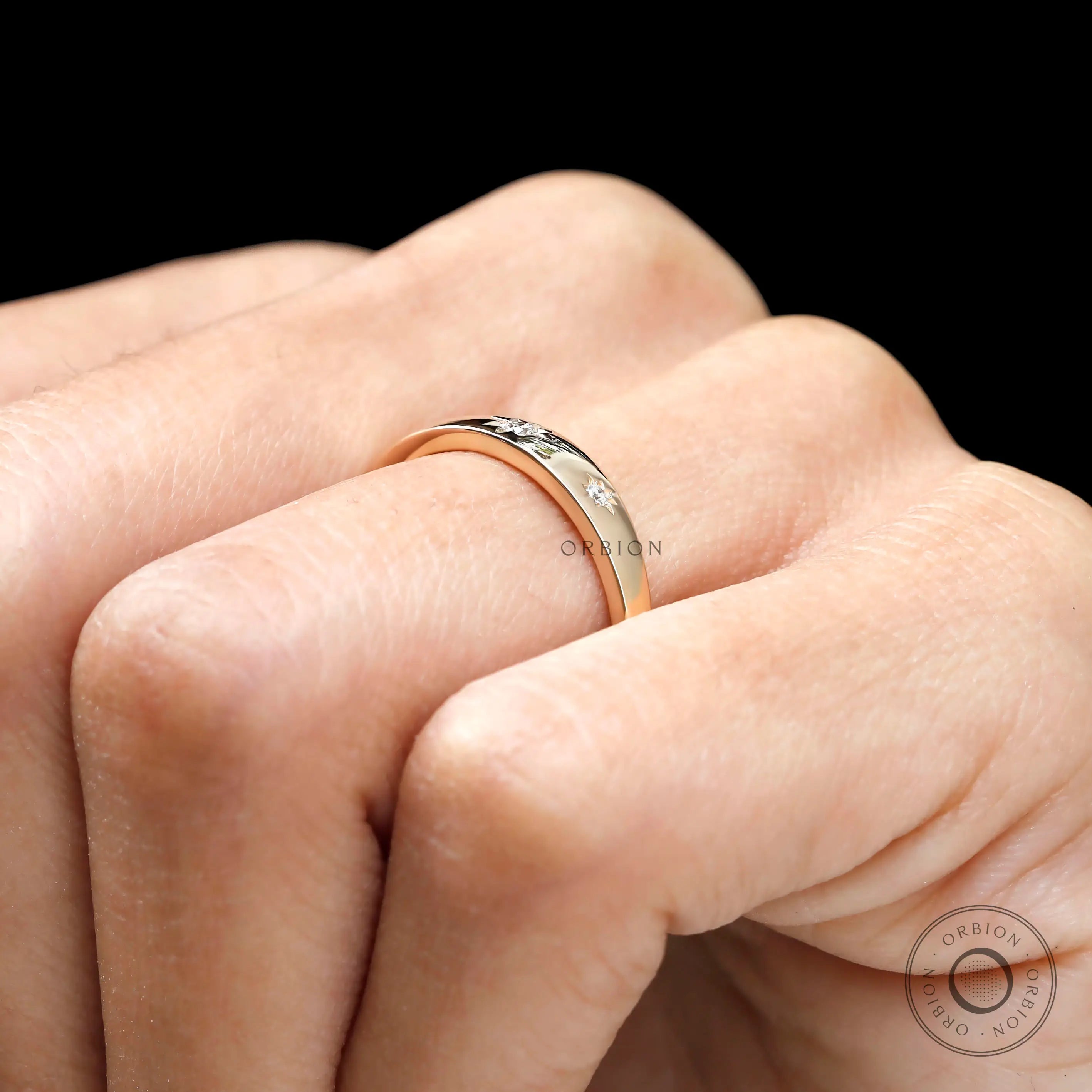 Close up of yellow gold band with starburst set diamonds.