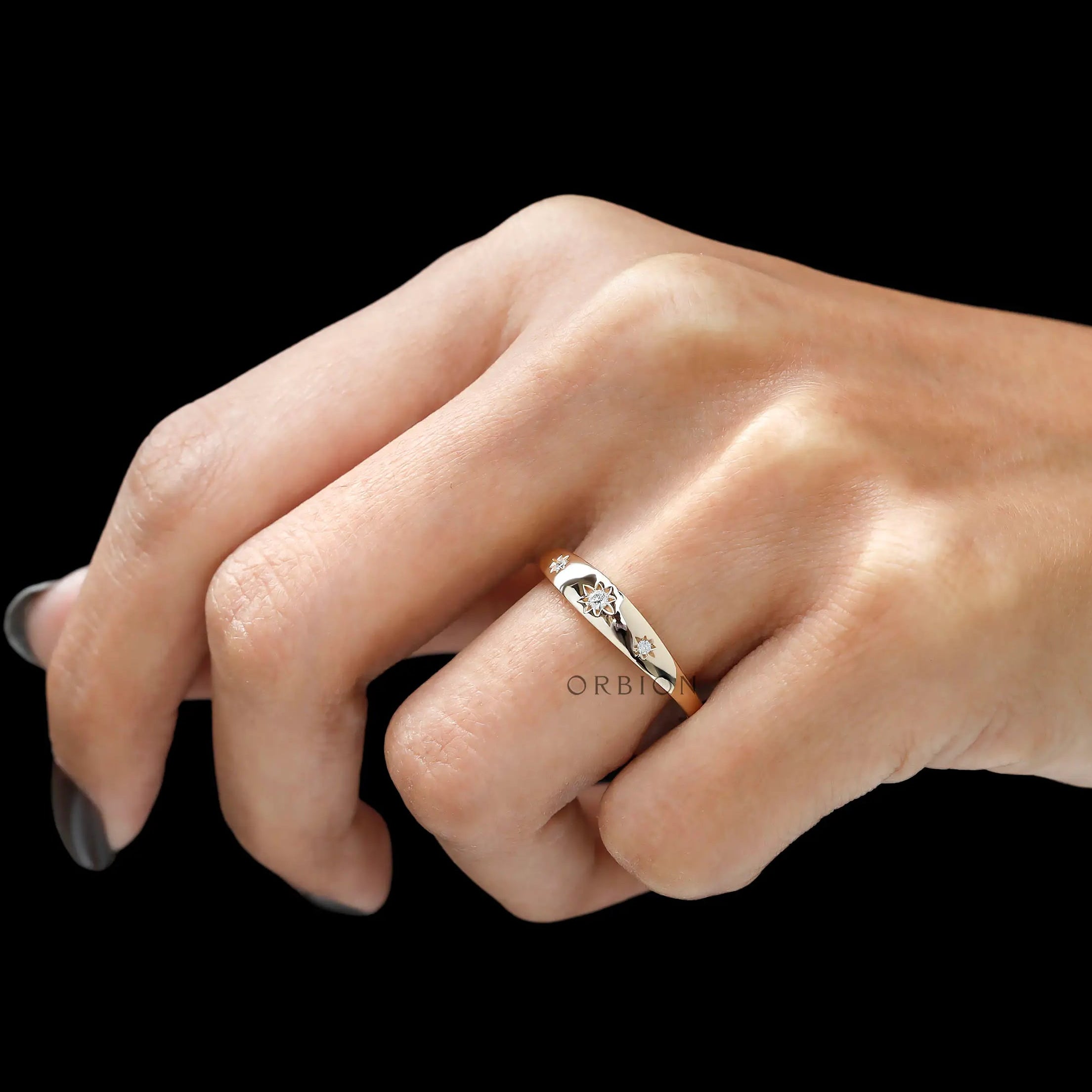 Angled worn view of slim gold band with three diamond stars.