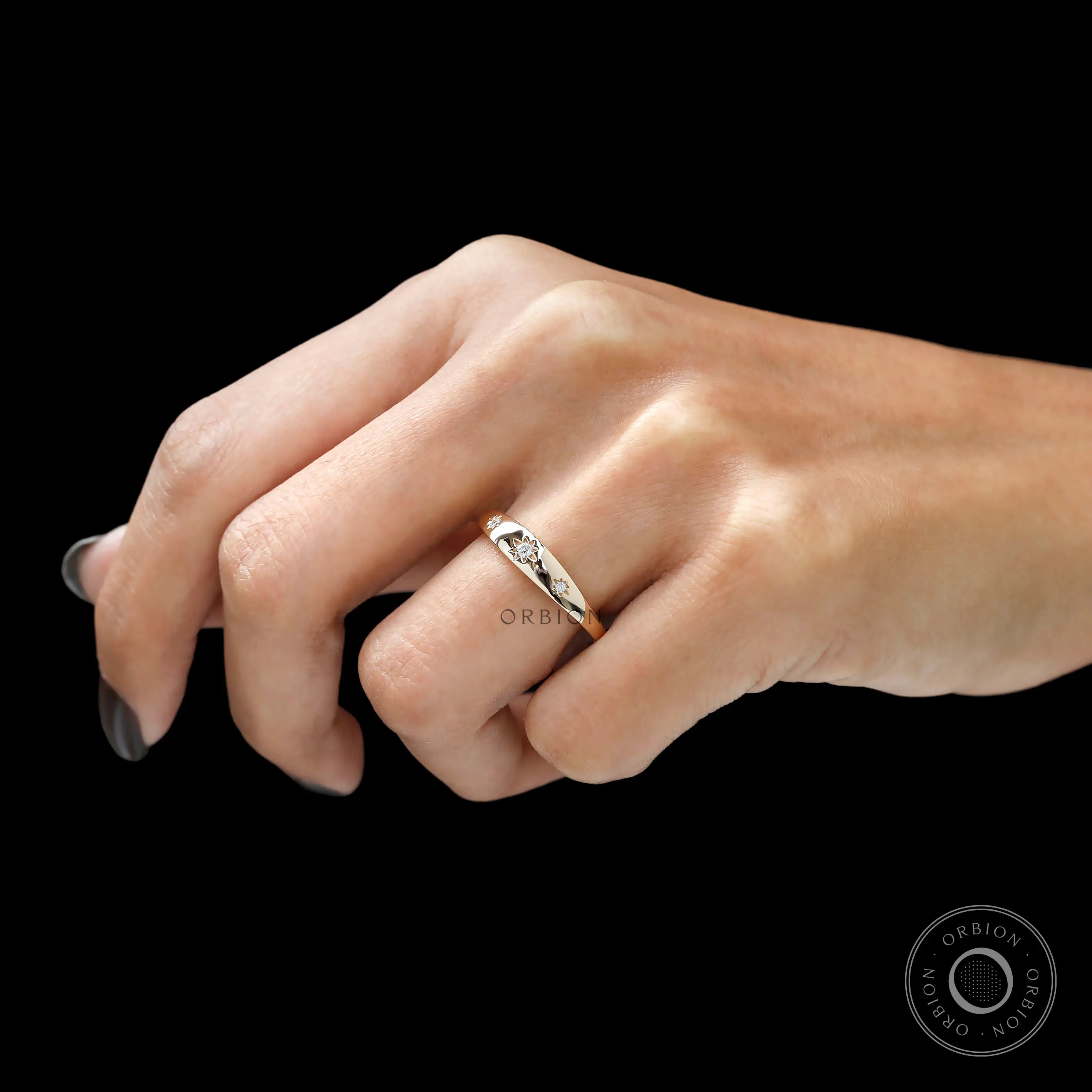 Angled worn view of slim gold band with three diamond stars.