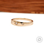 Angled front view of polished gold band with star set diamonds.