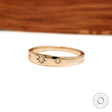 Angled front view of polished gold band with star set diamonds.