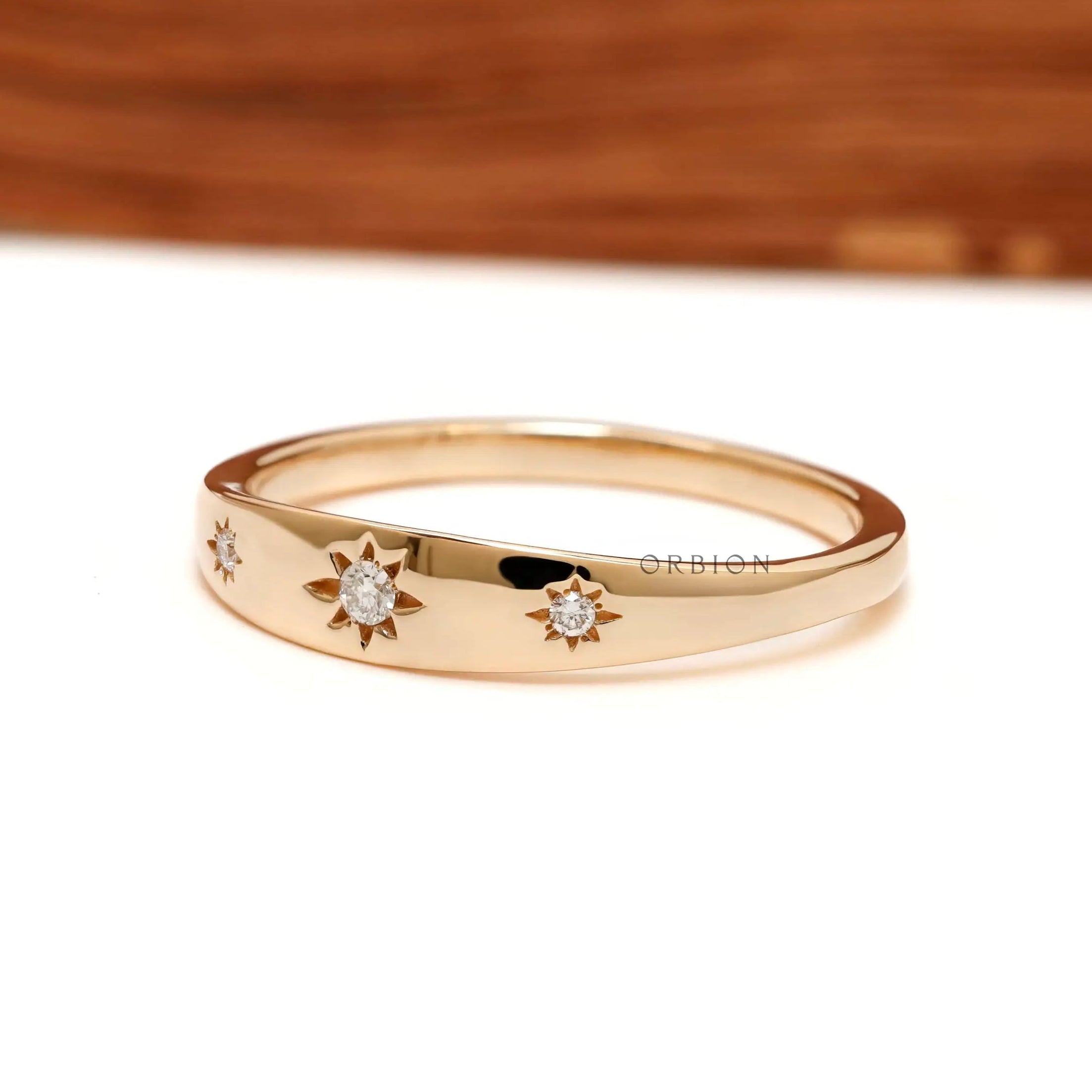 Angled front view of polished gold band with star set diamonds.