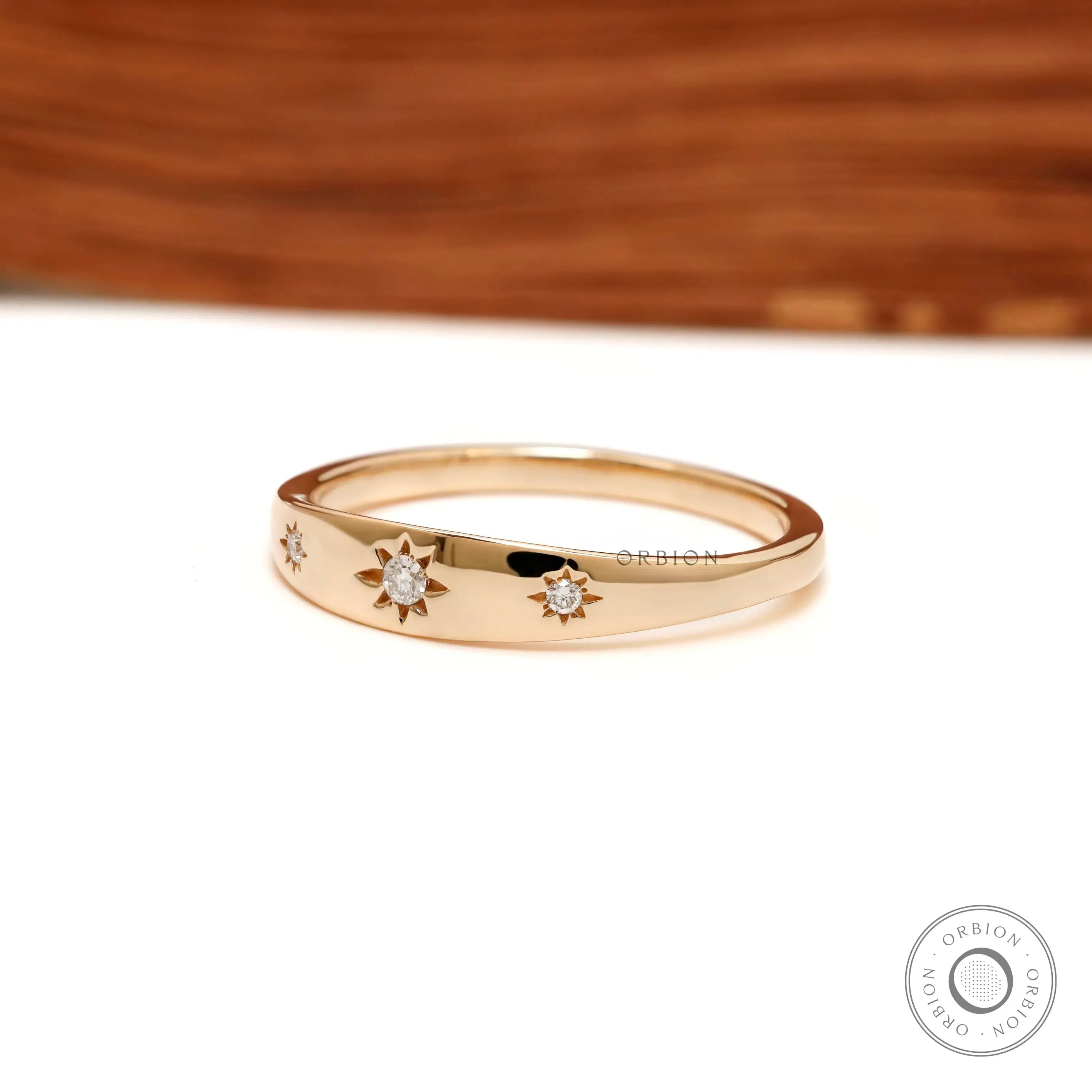 Angled front view of polished gold band with star set diamonds.