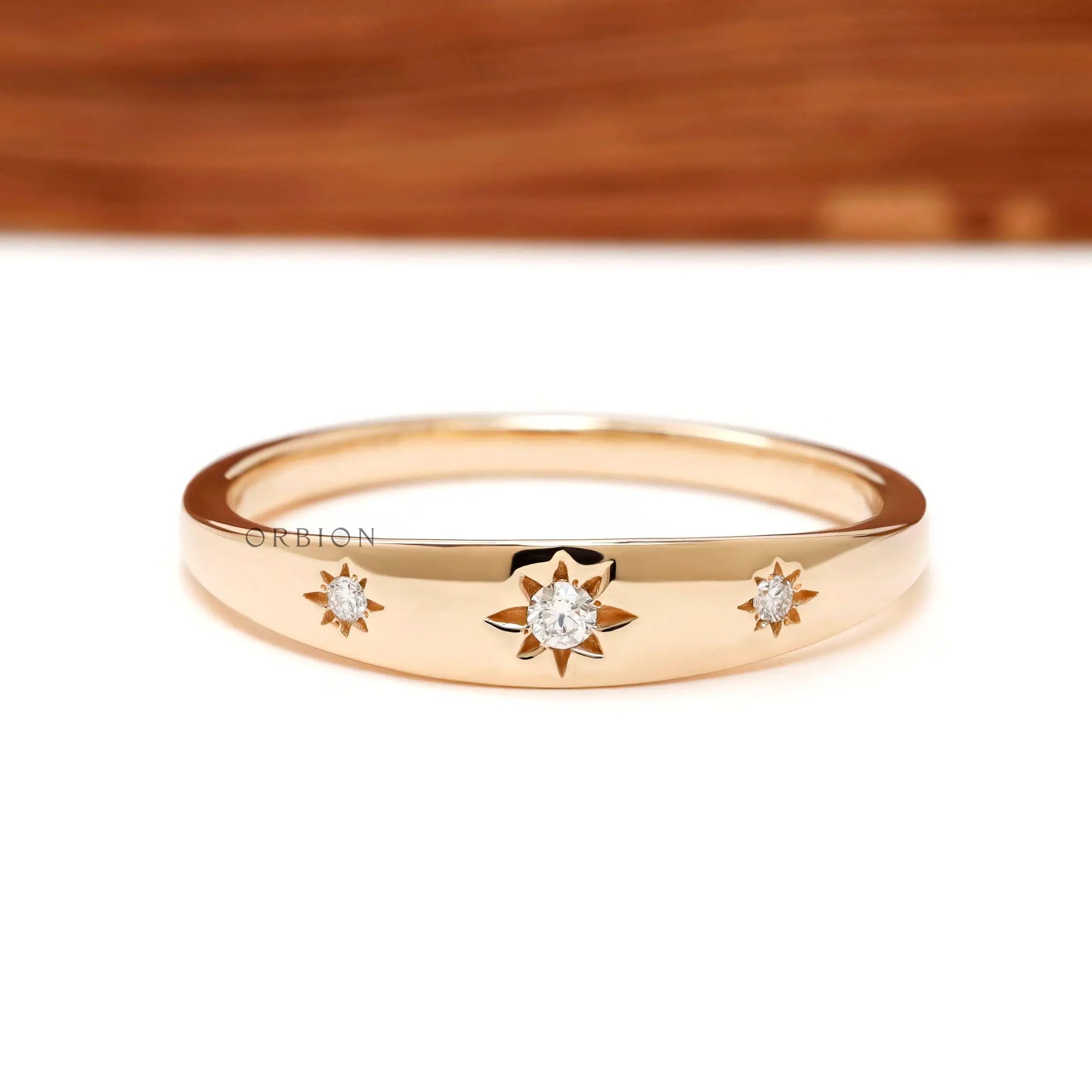 Front view of yellow gold band with three starburst set diamonds.