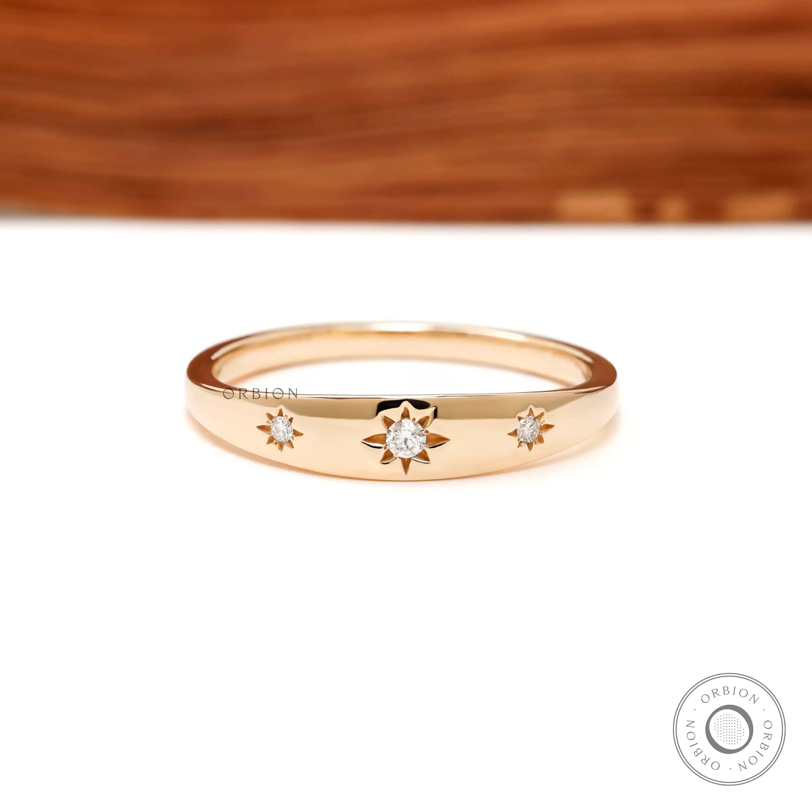 Front view of yellow gold band with three starburst set diamonds.