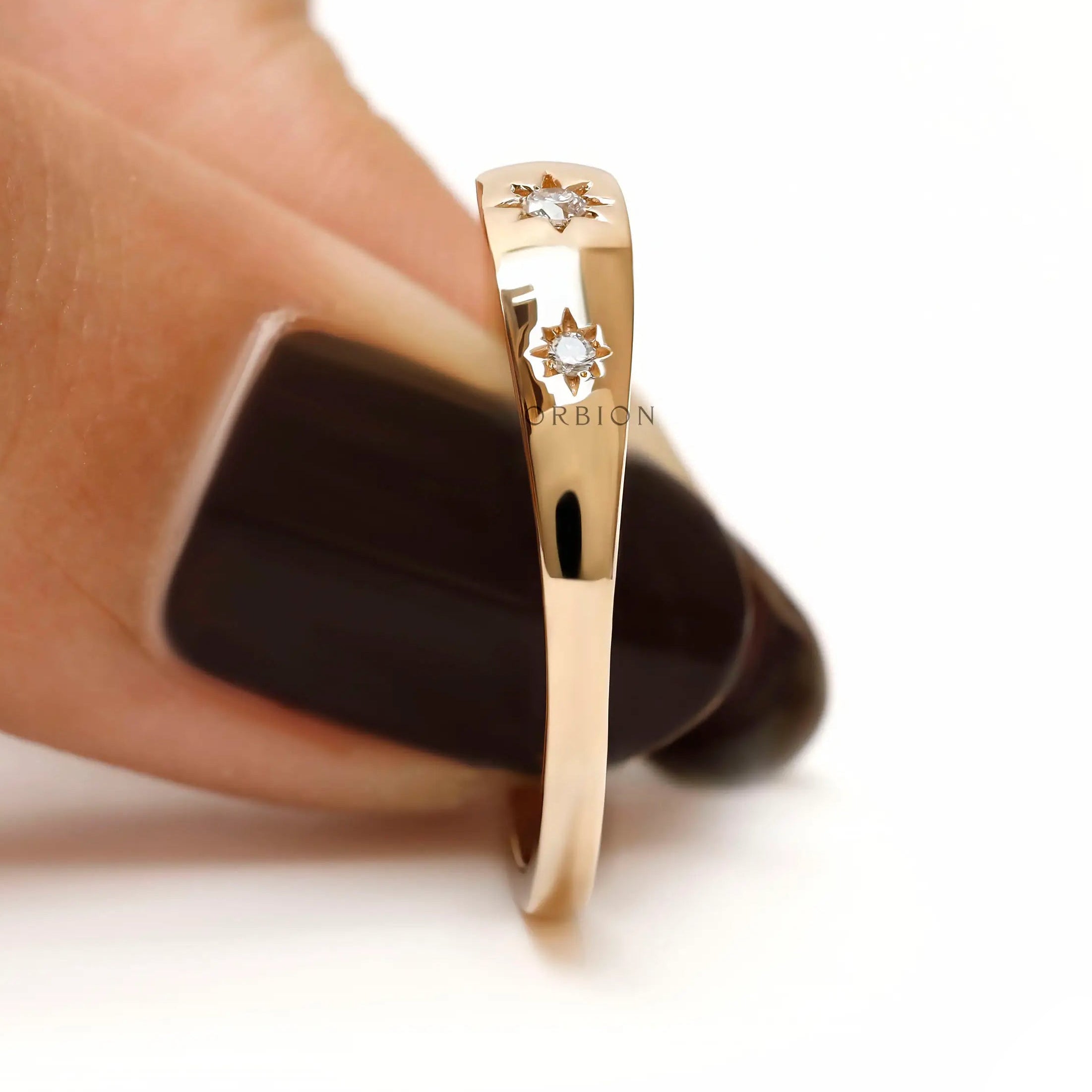 Side held view of tapered yellow gold band with star set diamonds.