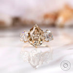 Light champagne pear old mine cut moissanite three stone ring in yellow gold