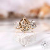 Light champagne pear old mine cut moissanite three stone ring in yellow gold
